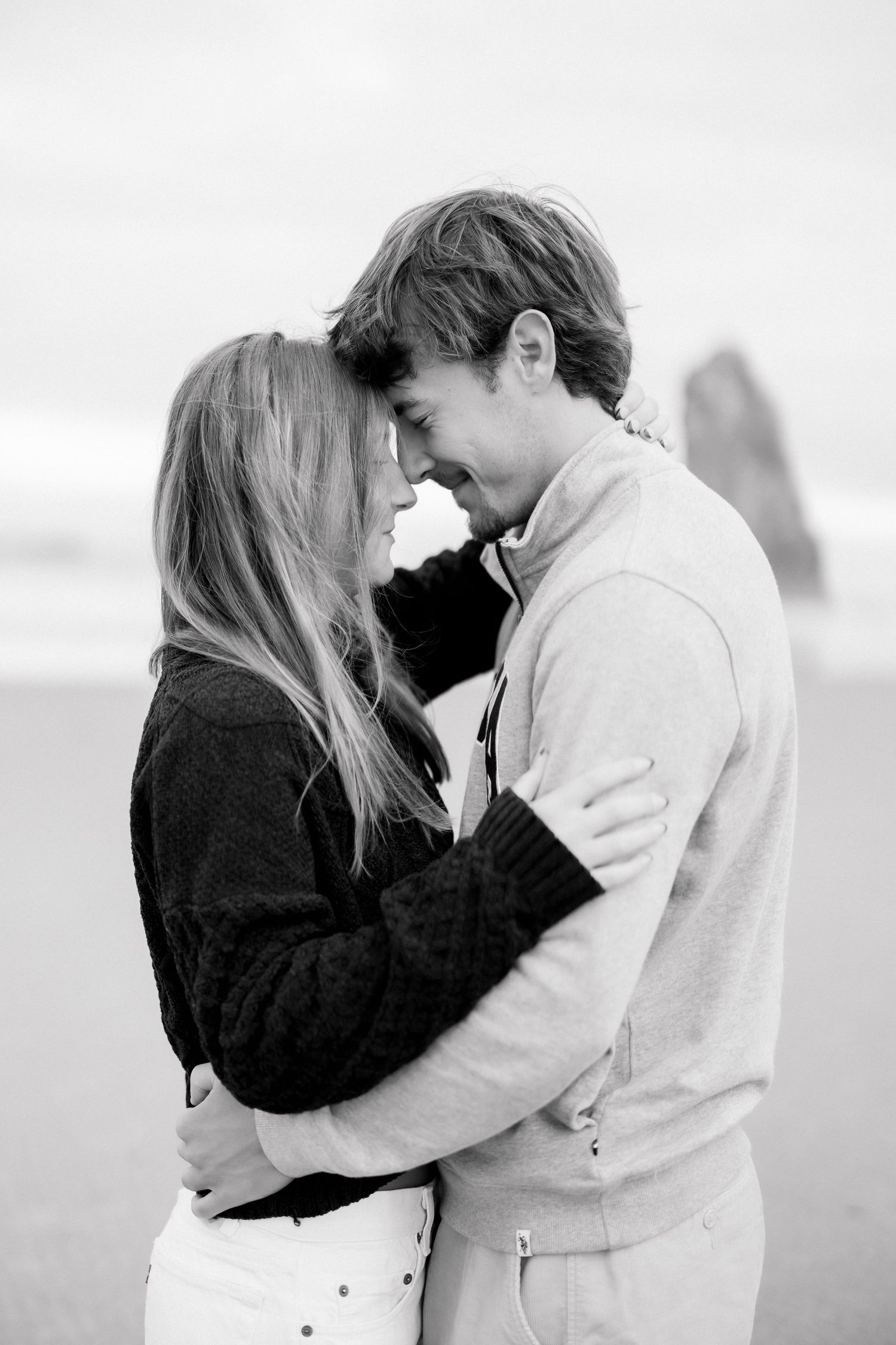 Black and white photo of a couple embracing and smiling on a beach.