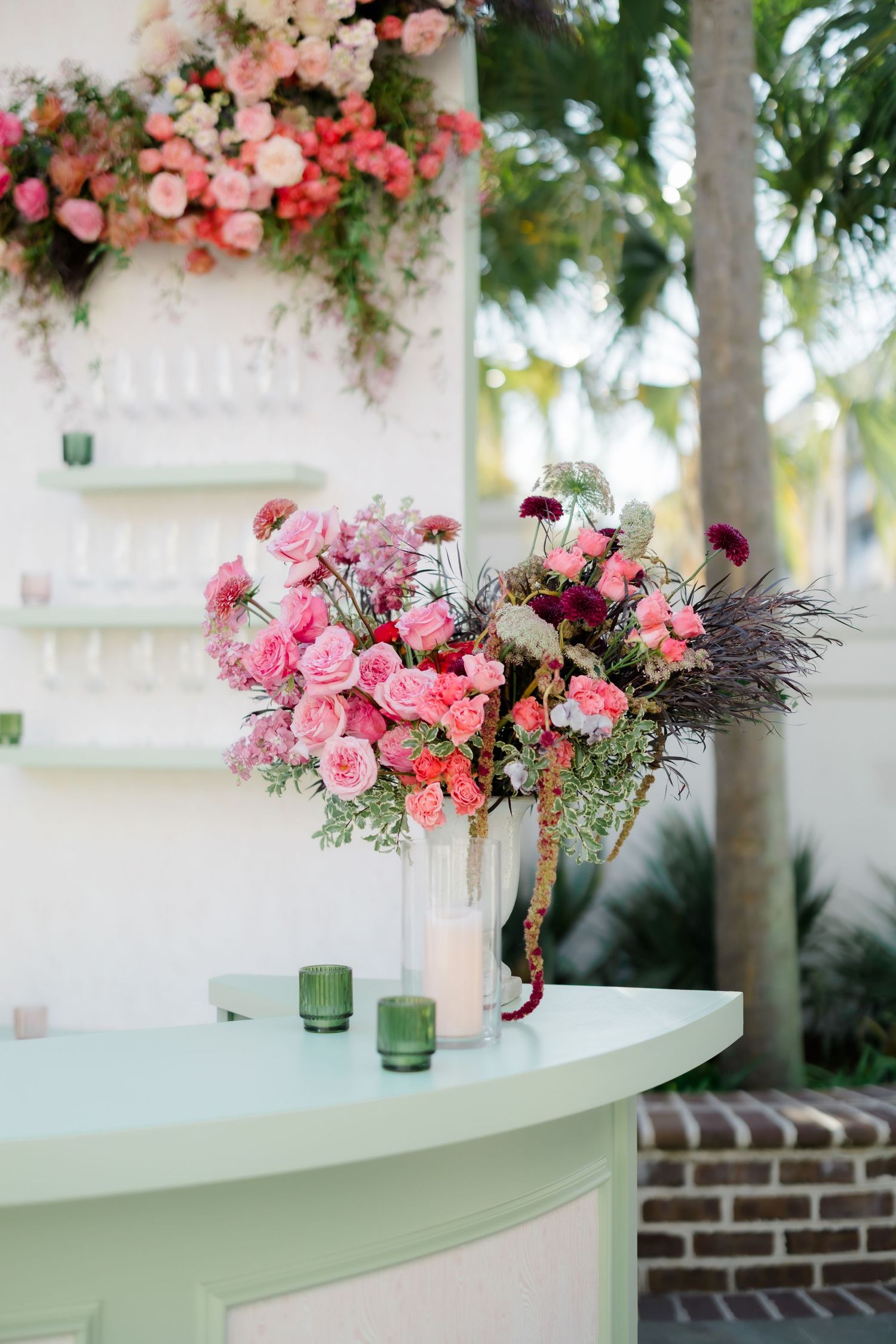 Elegant curved bar display with pink floral arrangements and greenery decorations.