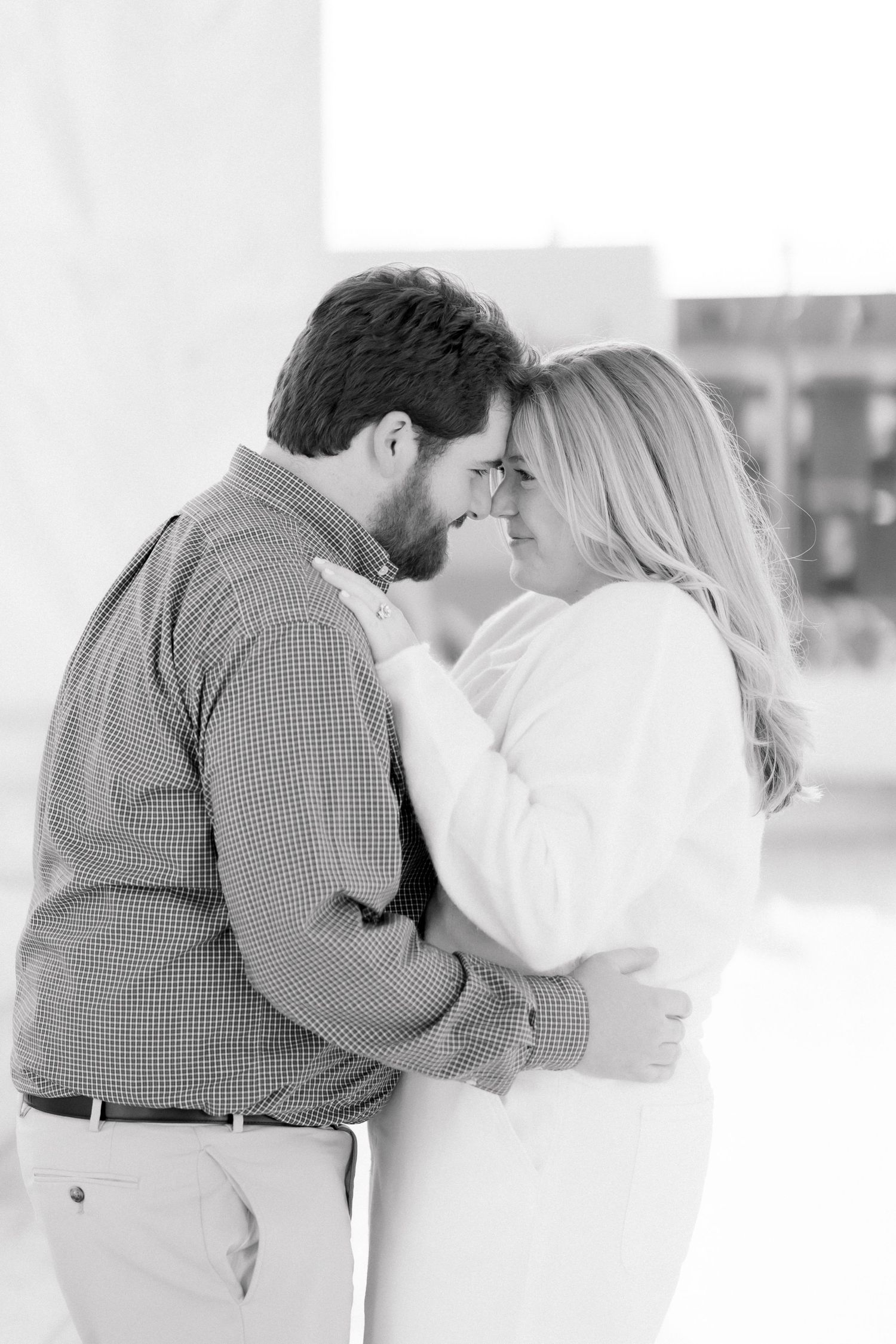 Black and white image of couple touching foreheads and embracing tenderly during engagement session.