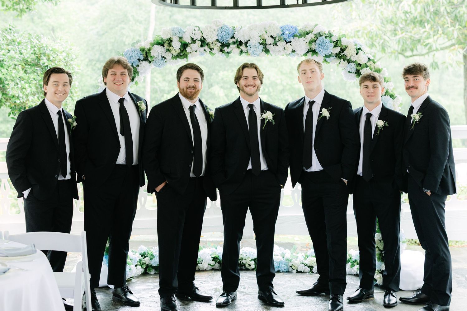 Groom and groomsmen portrait with blue and white floral arch