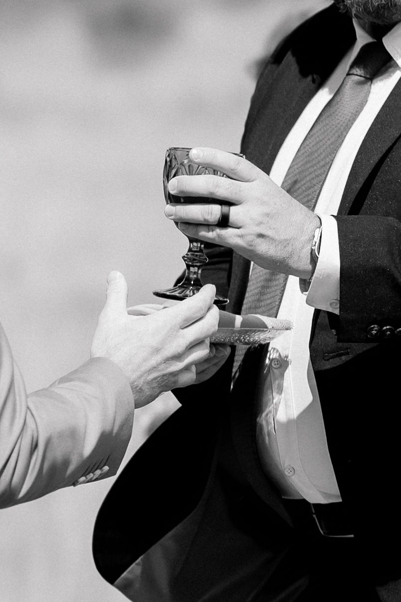 Black and white photo of two men in suits sharing a decorative goblet at a formal event.