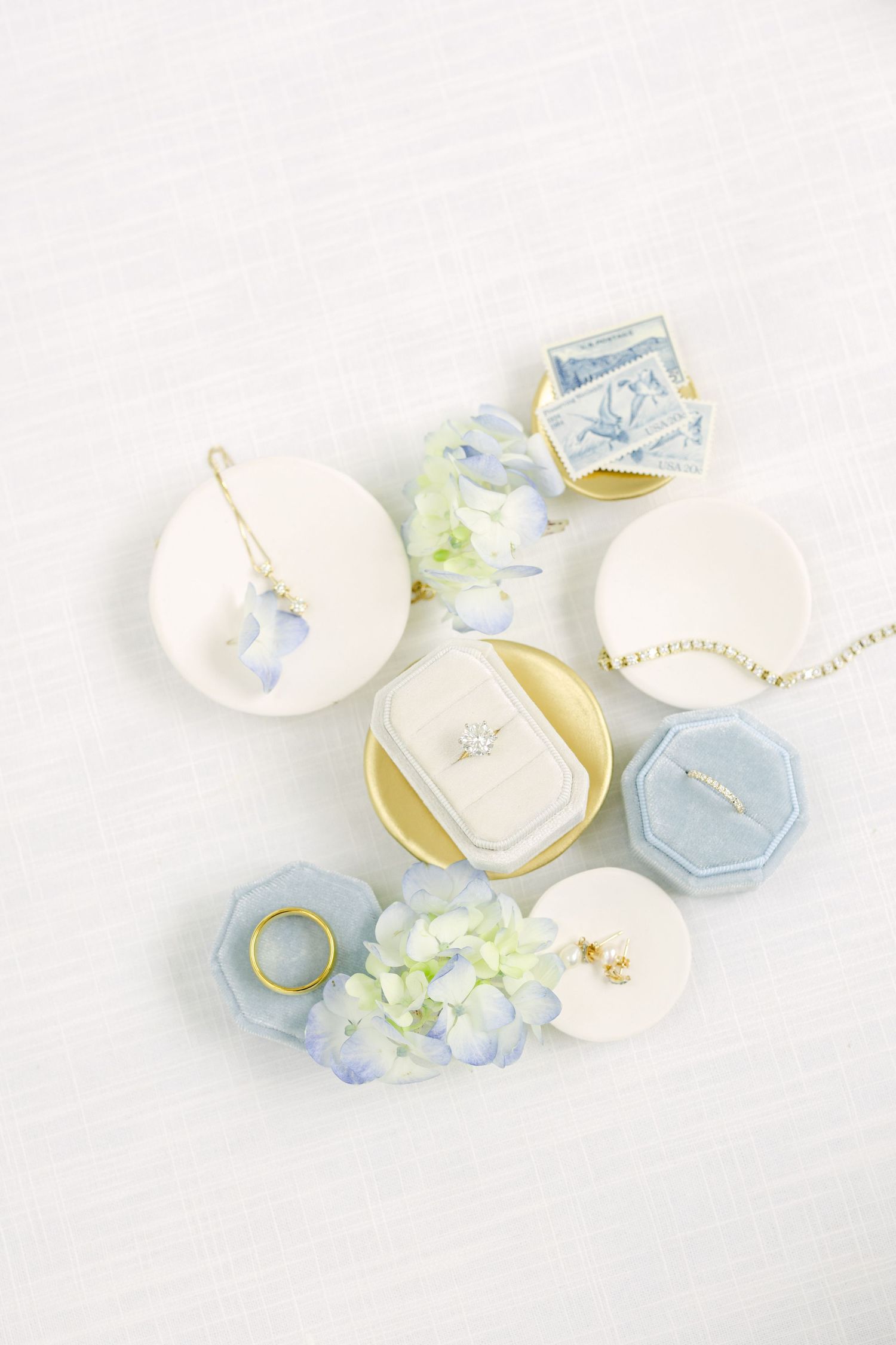 Delicate porcelain jewelry dishes in soft blue and white with gold accents arranged on white background. Gold and diamond jewelry.