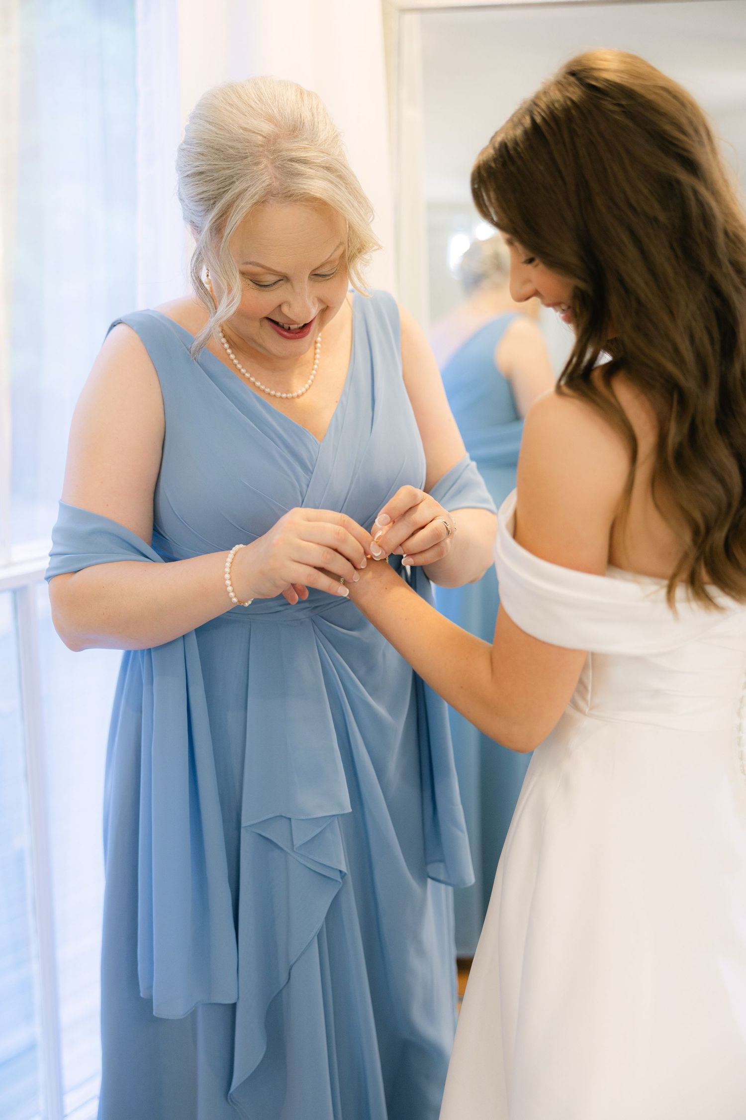 Mother of the bride putting a bracelet on the bride.