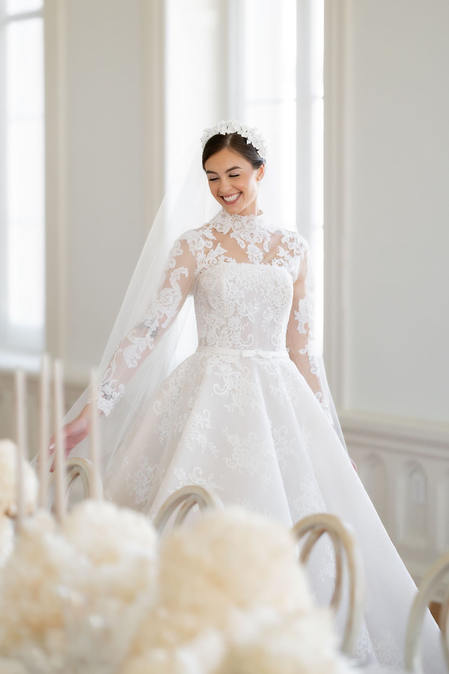Ethereal bridal portrait in lace gown with delicate veil in sunlit room.