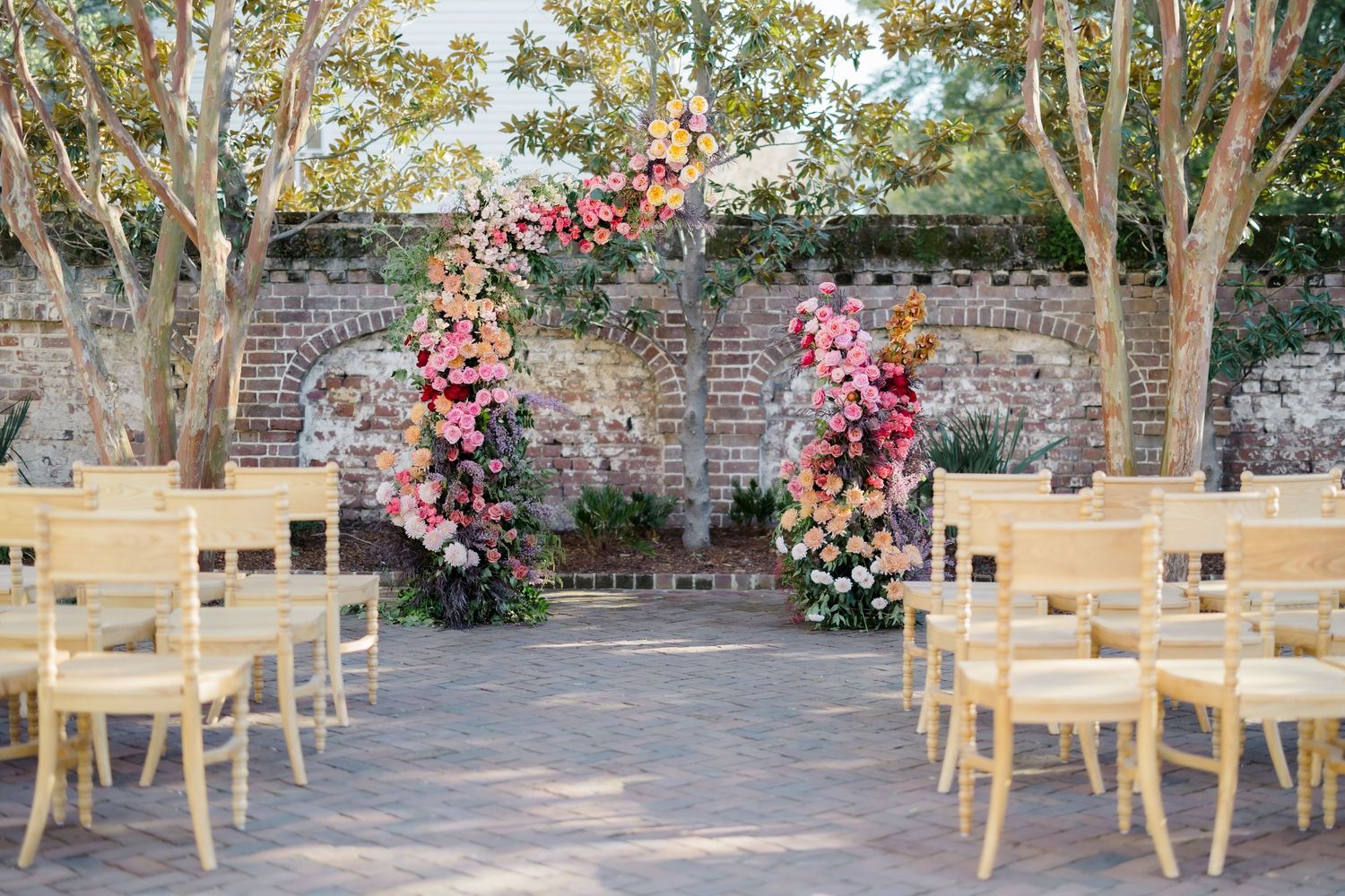 Outdoor wedding reception tables arranged with wooden chairs and floral centerpieces.