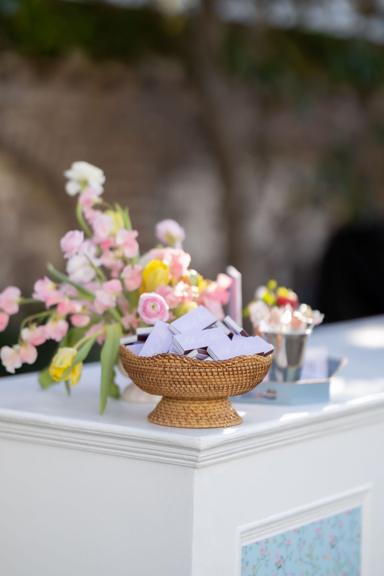 Pink and yellow flowers behind a basket of custom wedding matches.