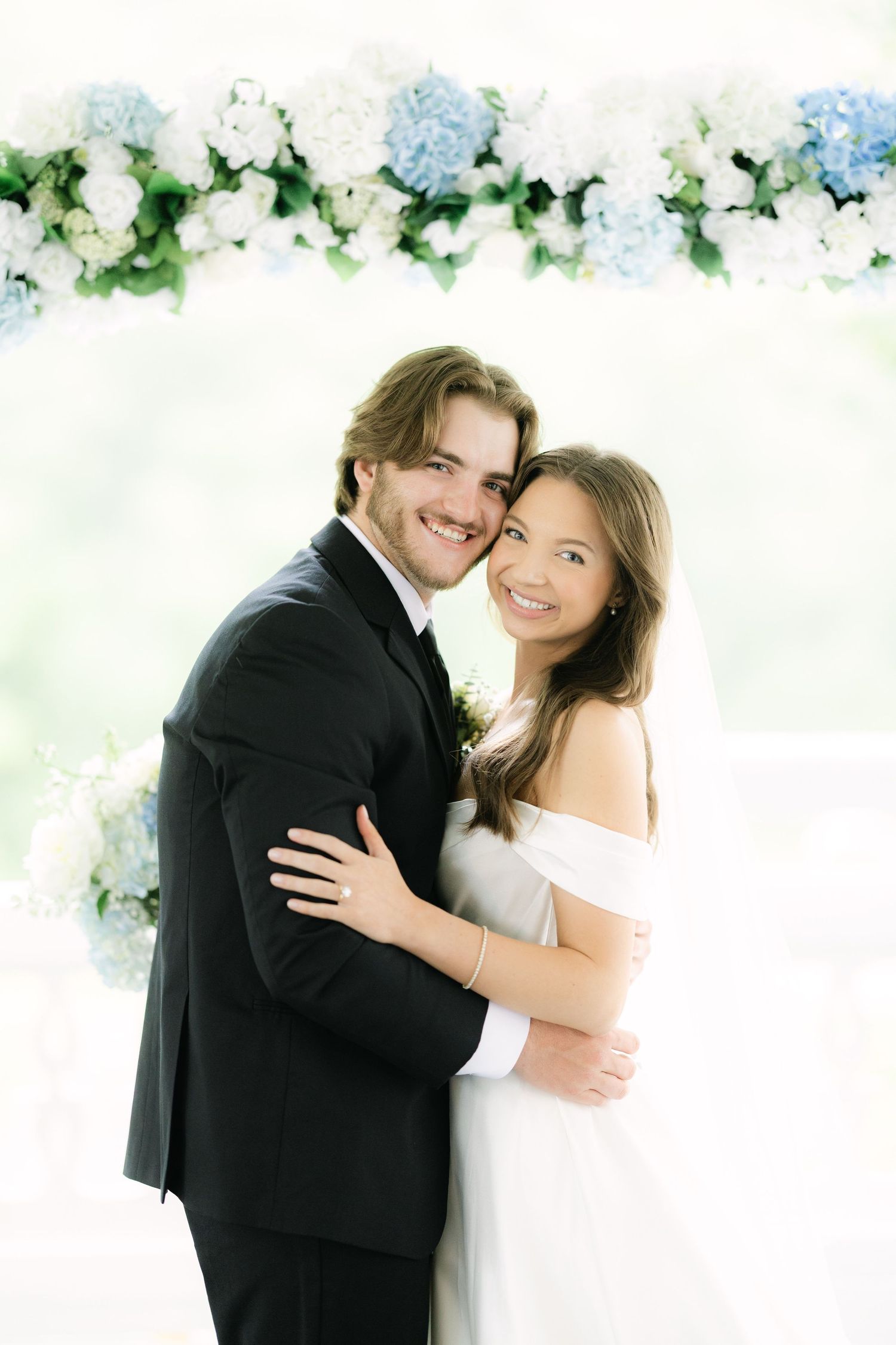 Bride and groom close up portrait under blue and white floral arch