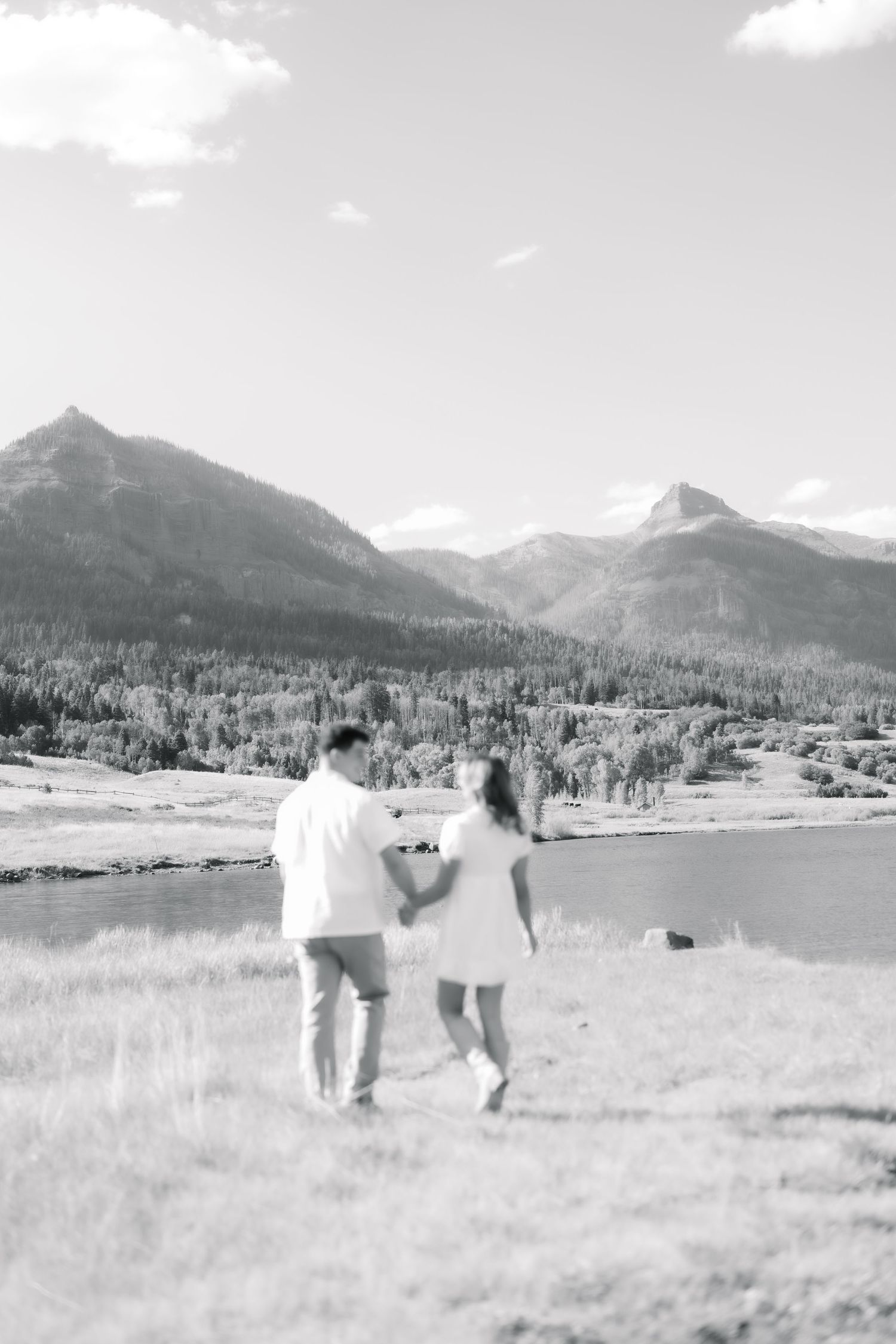 Two people walk through a scenic mountain meadow with snow-capped peaks in the distance. Williams Lake Reservoir near Pagosa Springs.