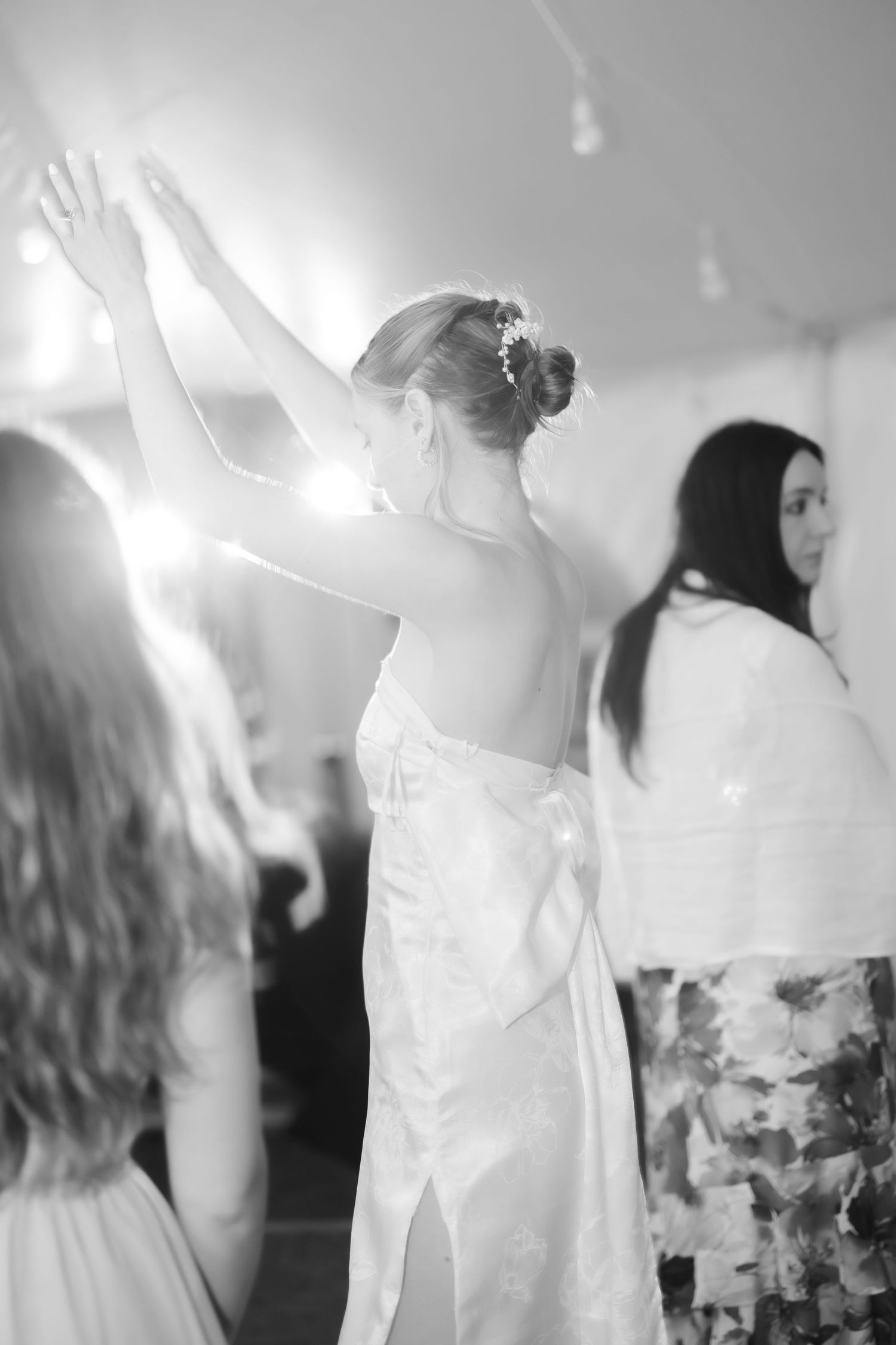 Black and white photo of a bride dancing with raised arm at wedding reception.