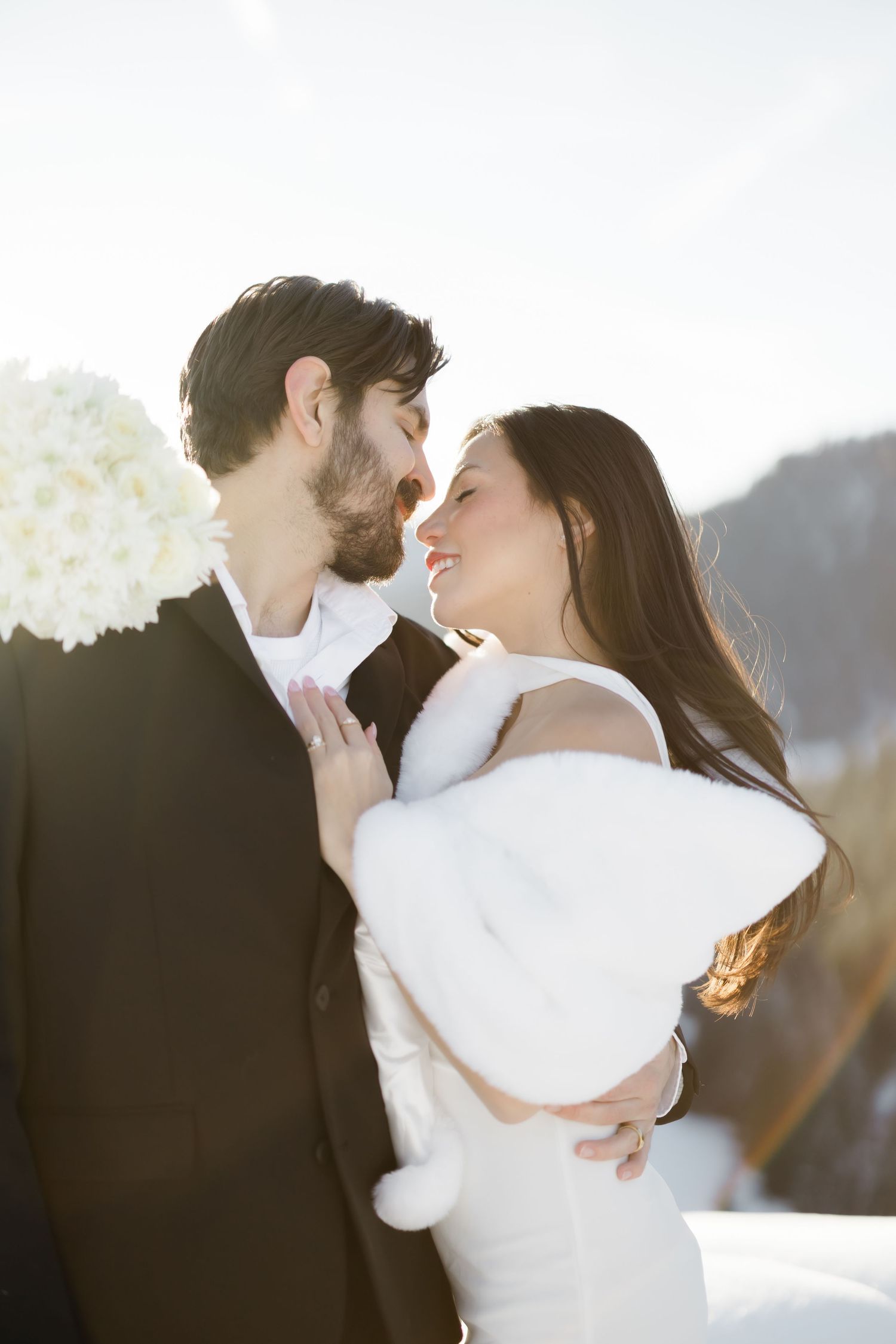 Bride and groom sharing a romantic moment in a snowy winter wedding setting, bride wearing white fur wrap.