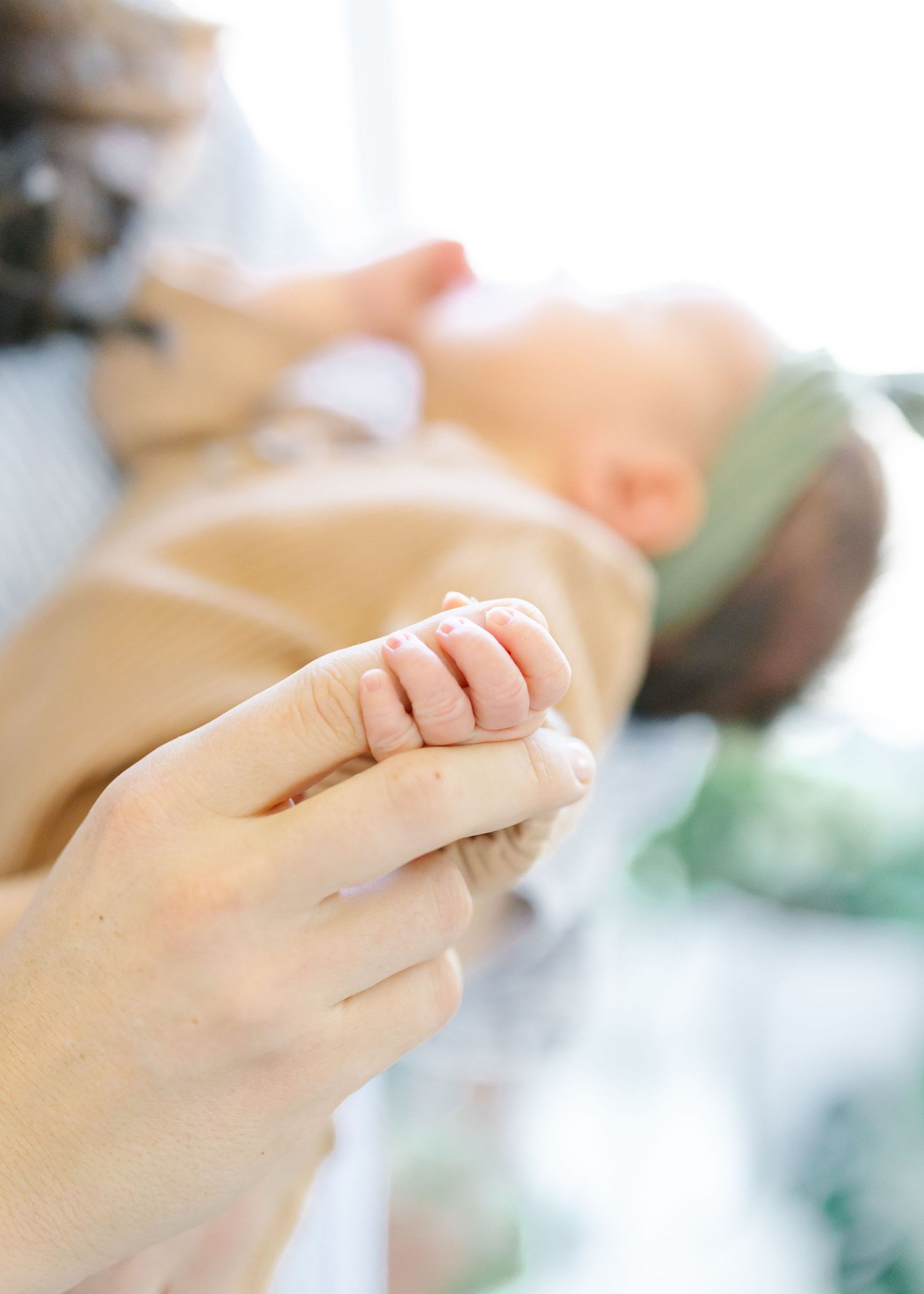 Close-up photo of a newborn hand holding a mother's finger.