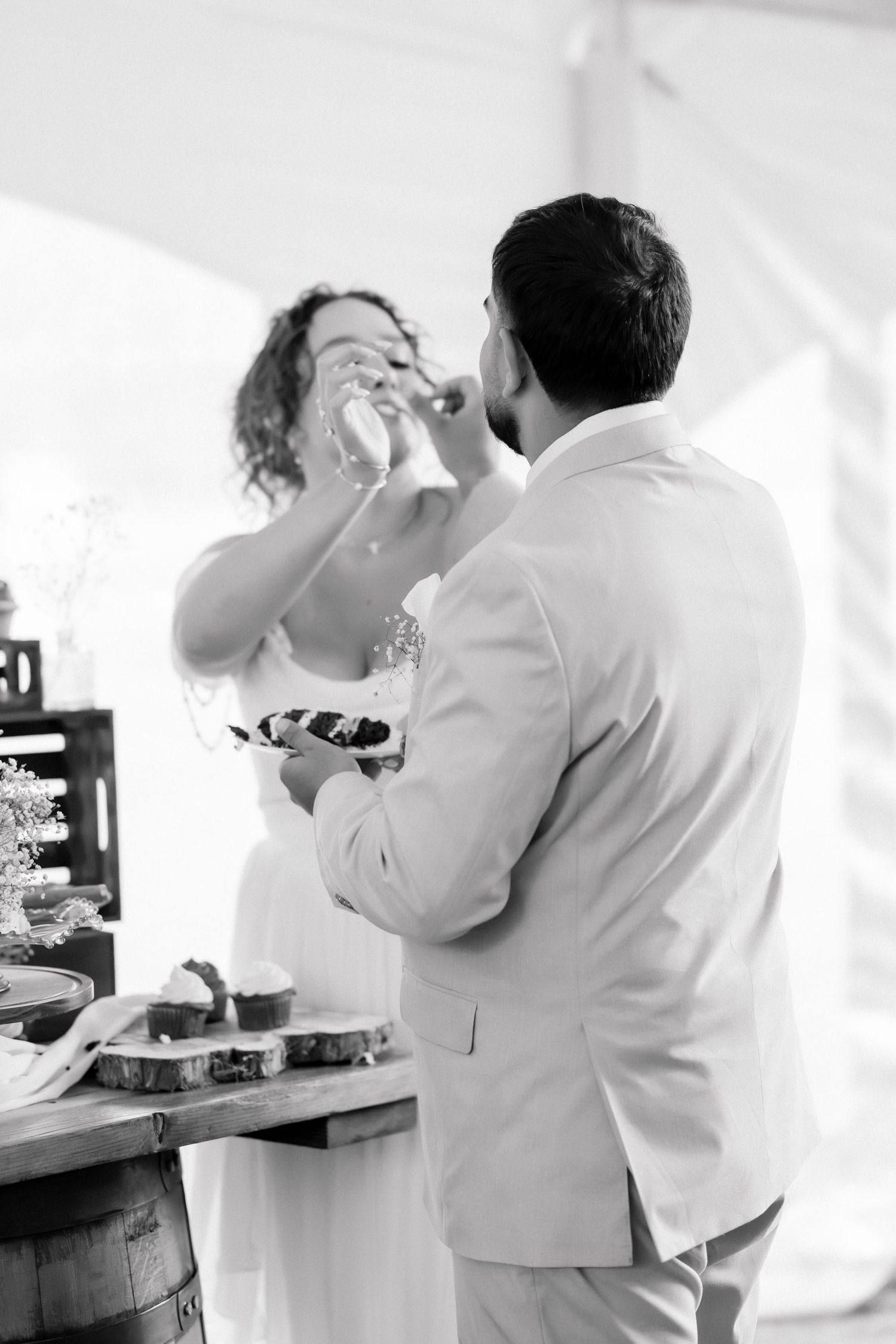 Black and white photo of bride and groom sharing cake at their wedding reception.
