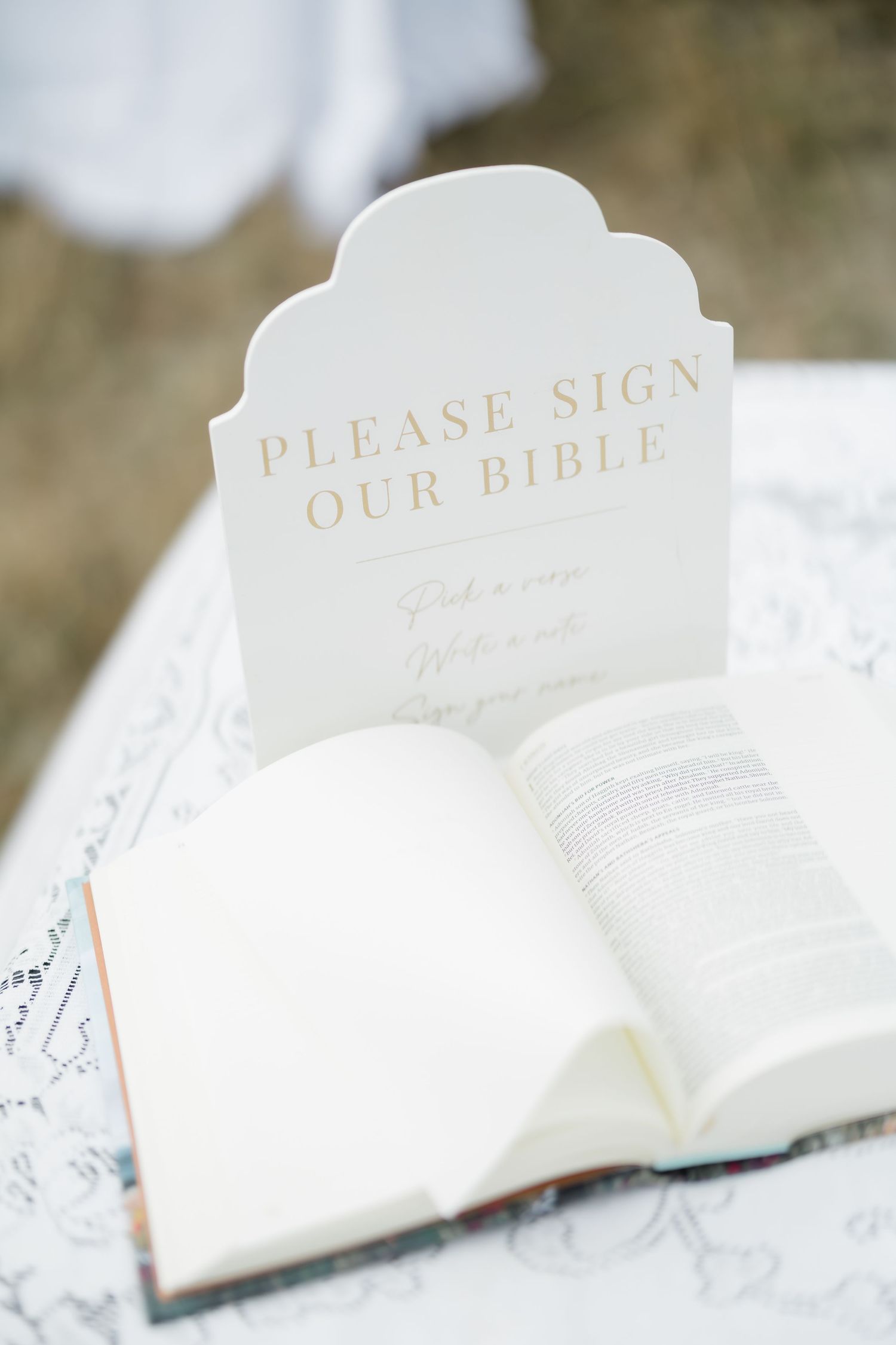 Elegant wedding Bible guest book with a white sign reading Please Sign Our Bible in gold lettering.