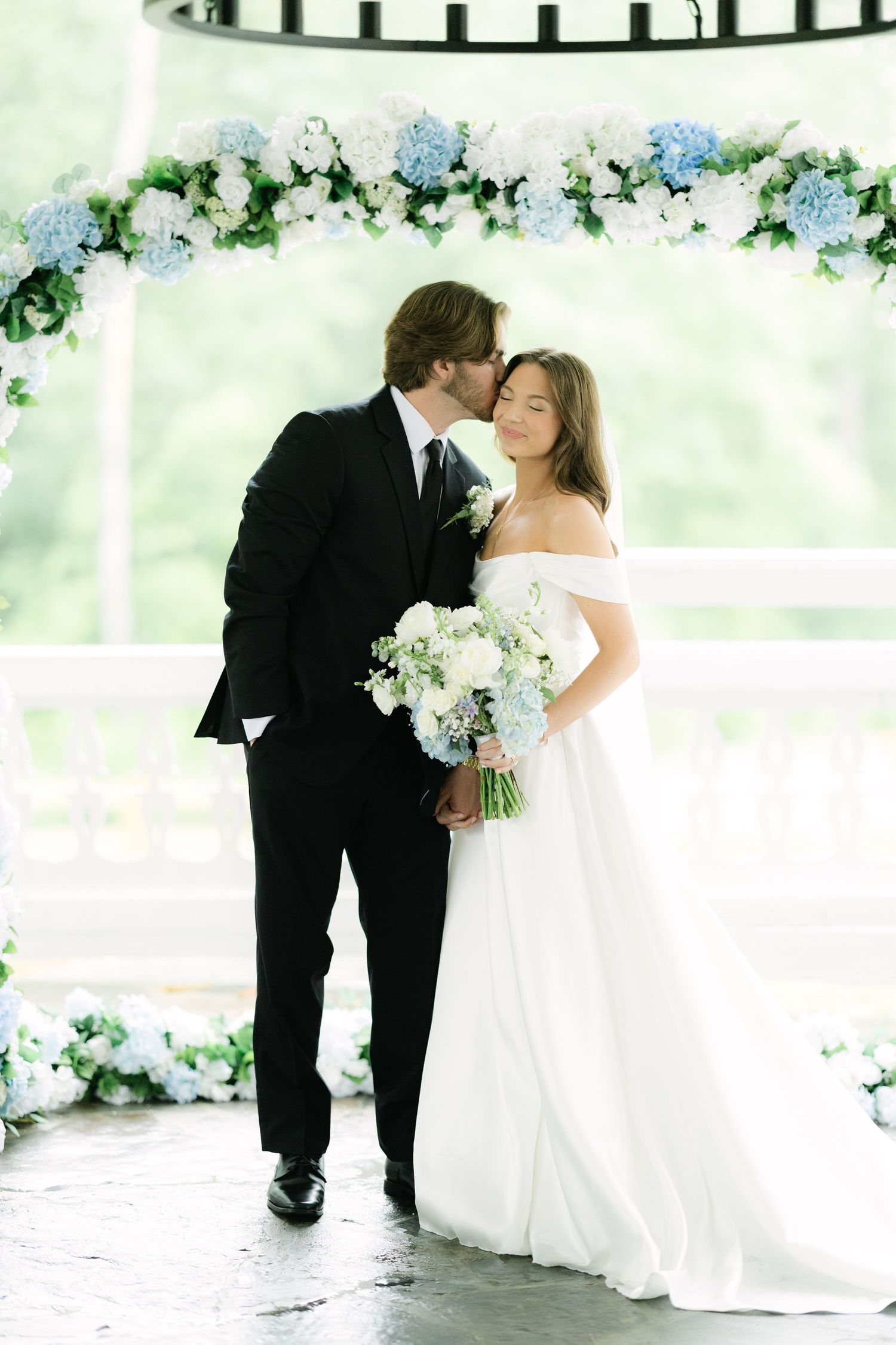 Bride and groom portrait under blue and white floral arch