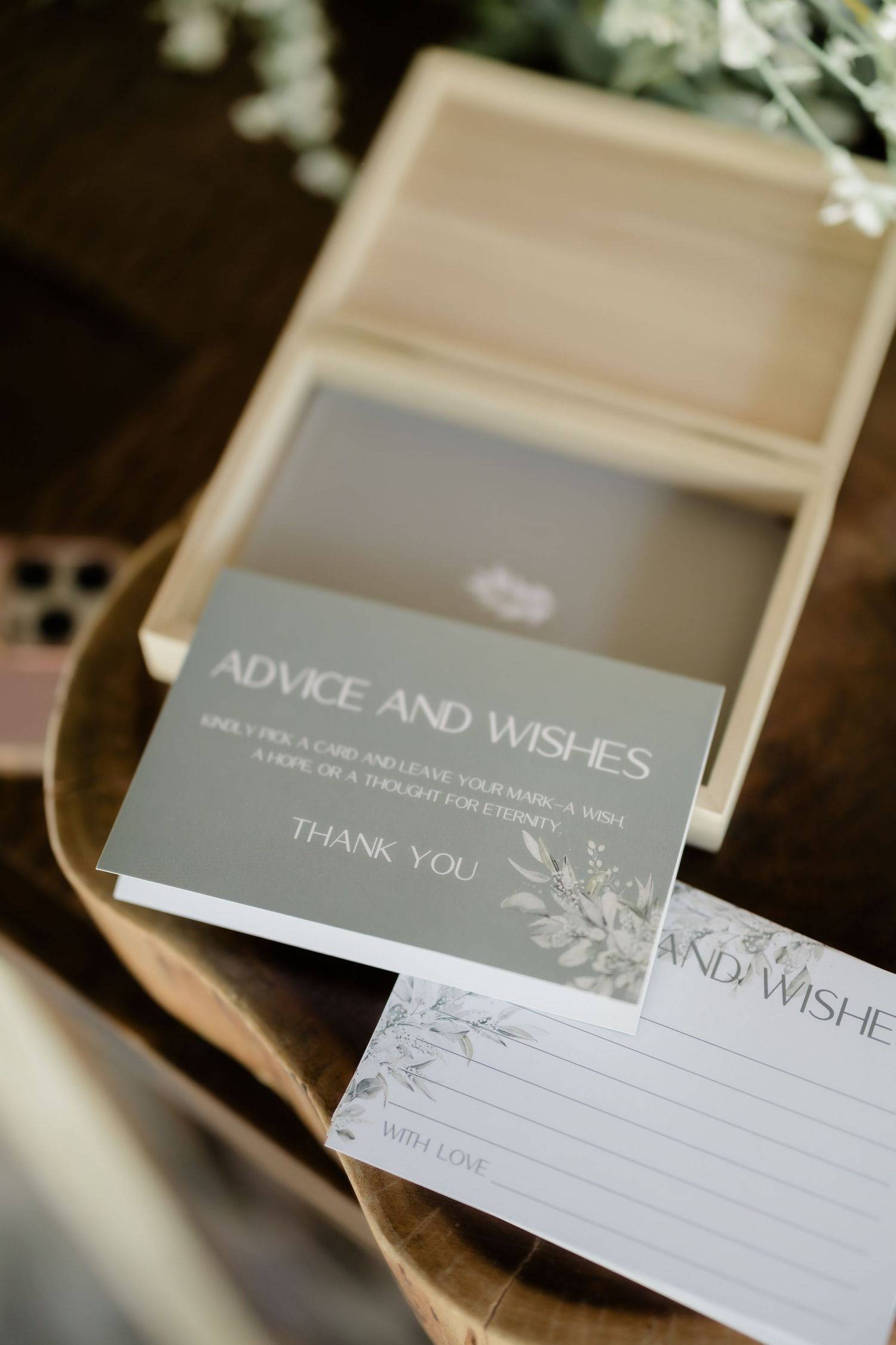 Elegant wedding advice and wishes cards displayed in a wooden box with floral accents for guests to leave messages.