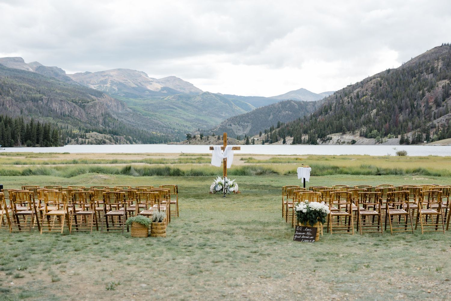 Outdoor mountain wedding ceremony setup with wooden chairs, floral arch, and stunning Colorado valley backdrop.