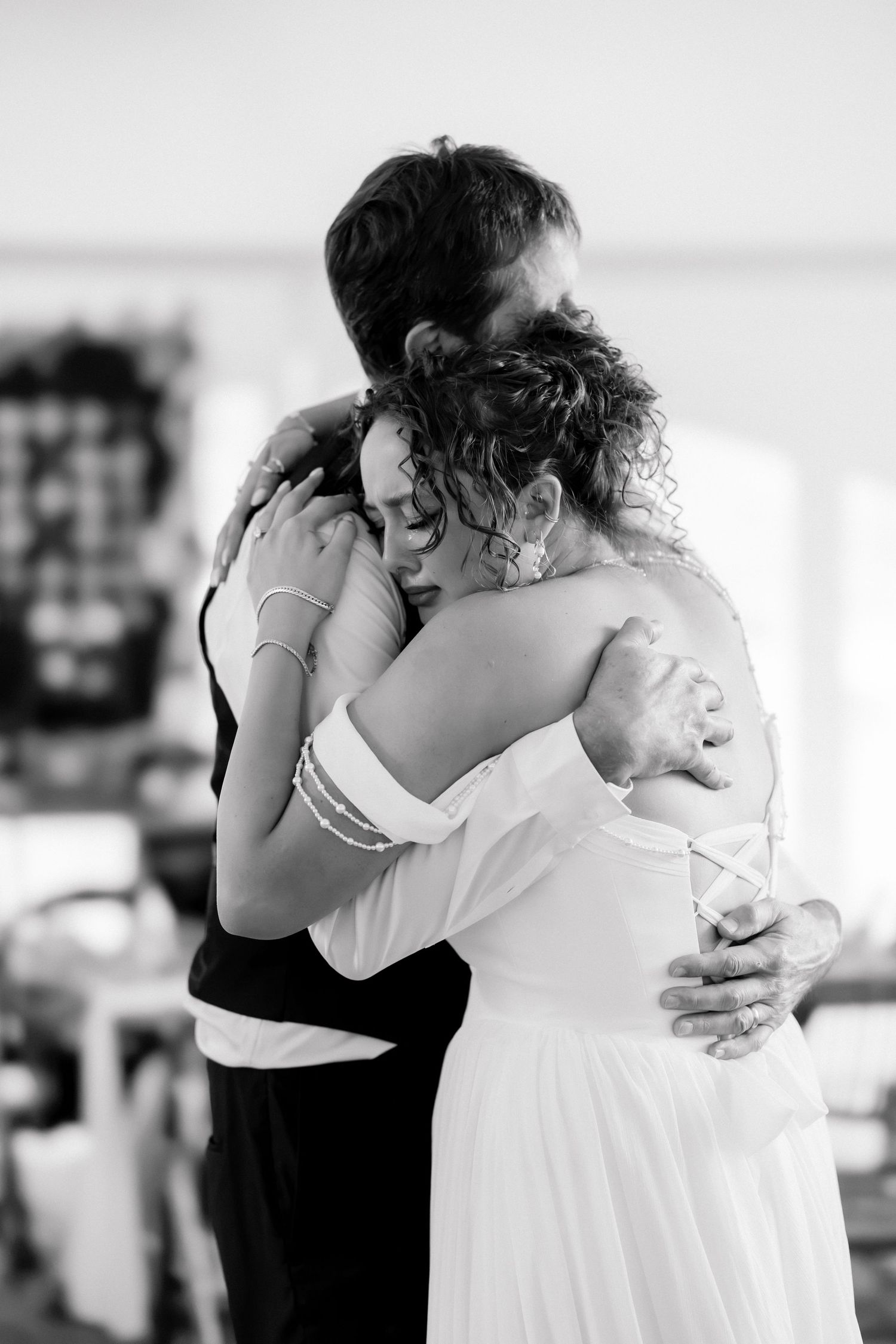 Black and white photo of bride and guest sharing an emotional embrace at wedding reception.