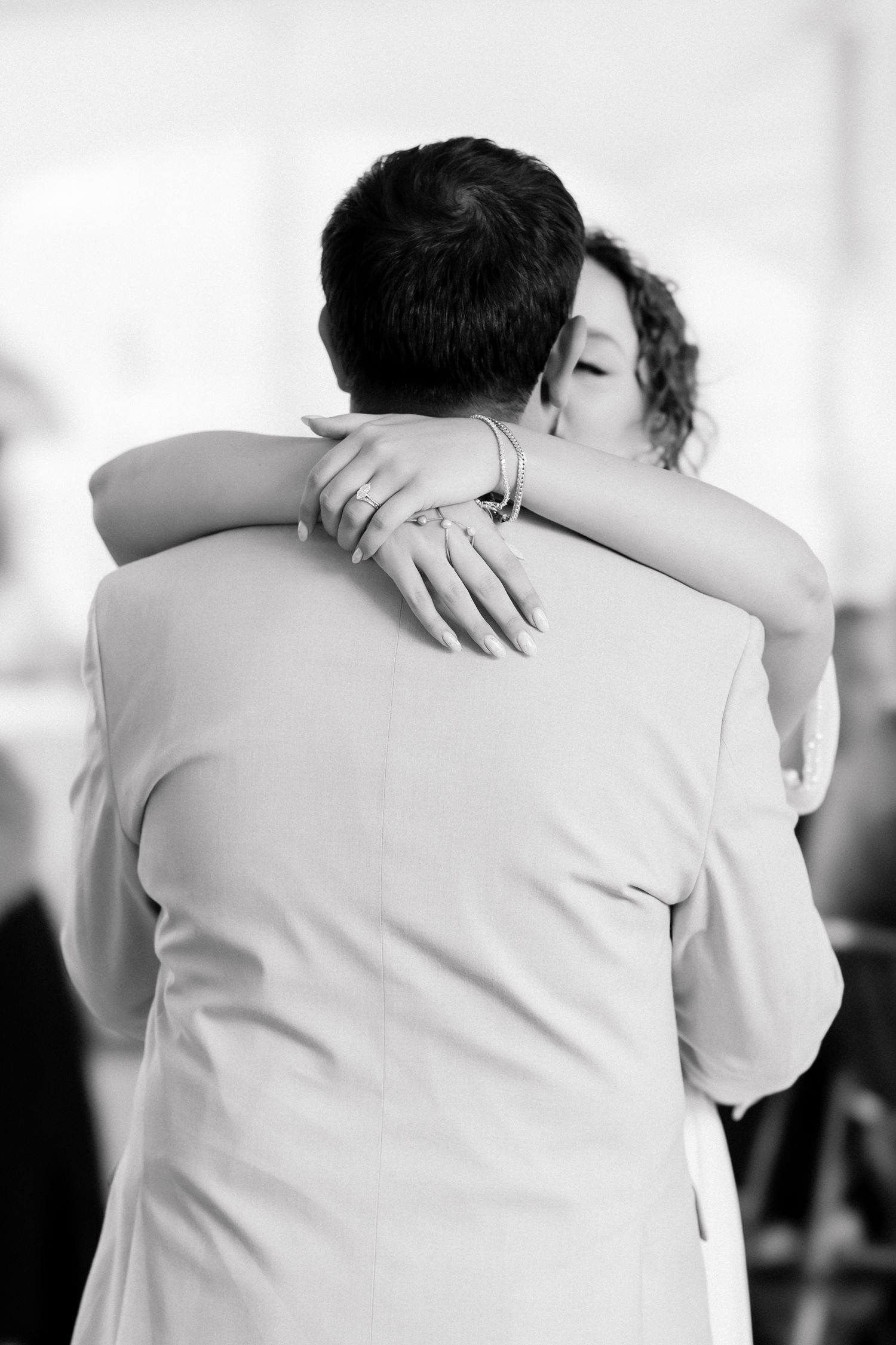 Black and white photo of a bride and groom sharing an emotional first dance embrace.