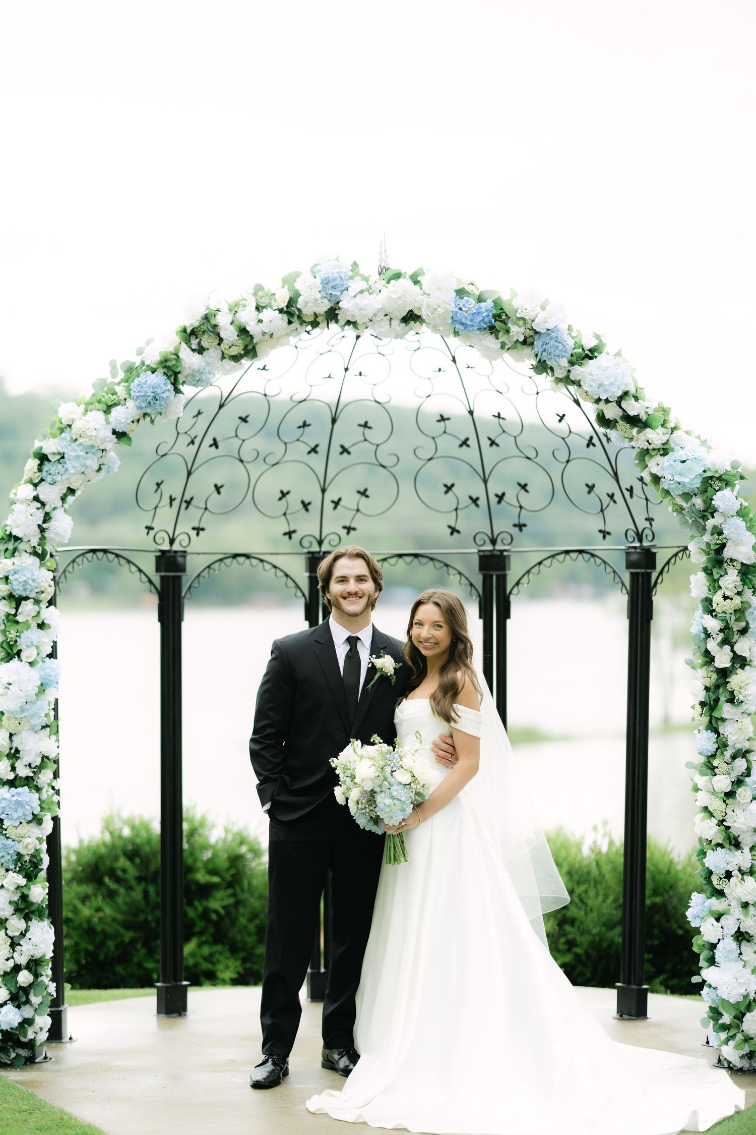 Bride and groom under blue and white floral arch