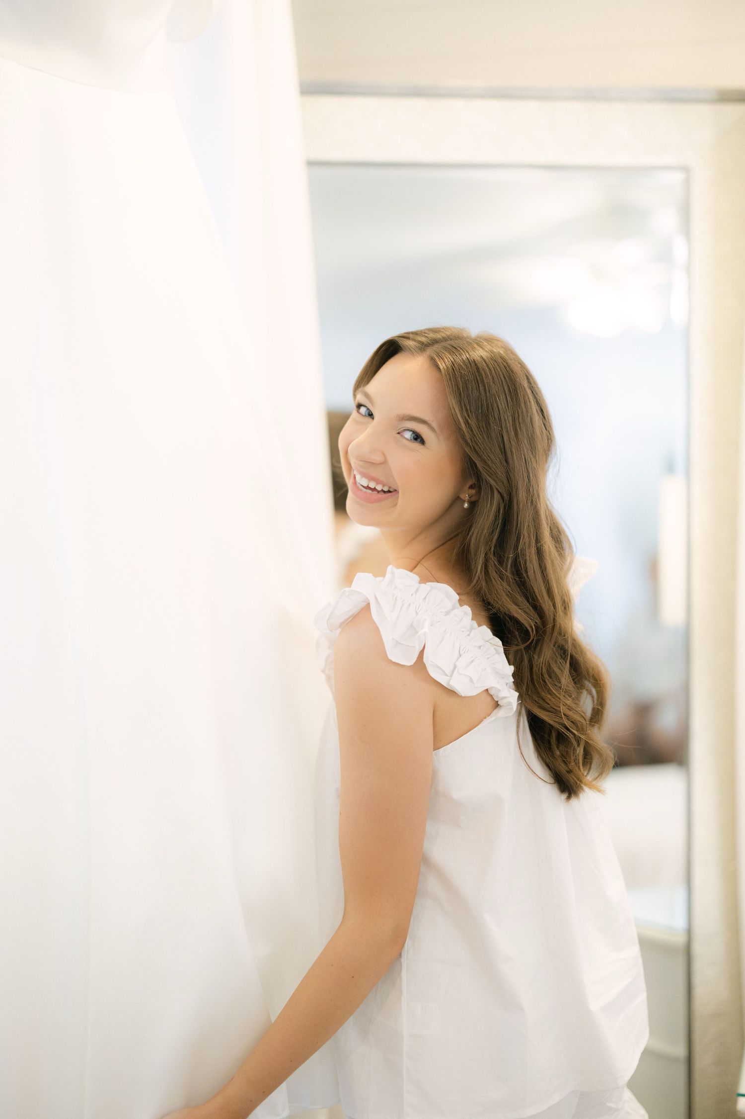Bride looking back and smiling while getting ready