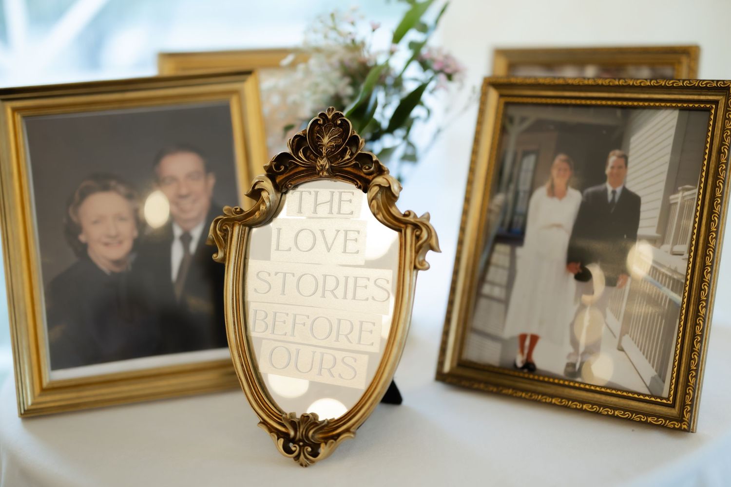 Gold-framed family photos displayed with an ornate mirror engraved with 