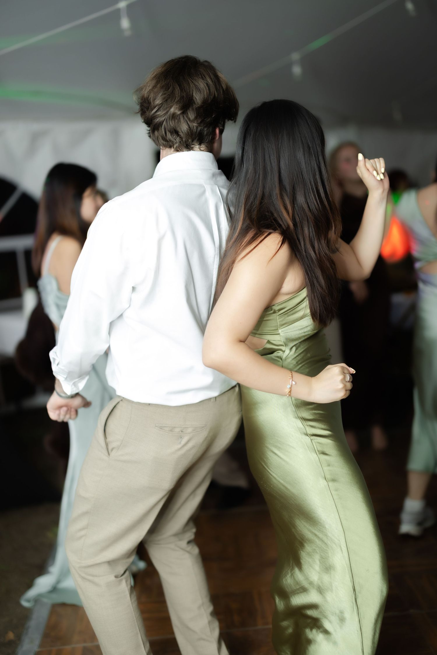 Couple dancing closely at a formal event, man in white shirt and woman in elegant green satin dress.