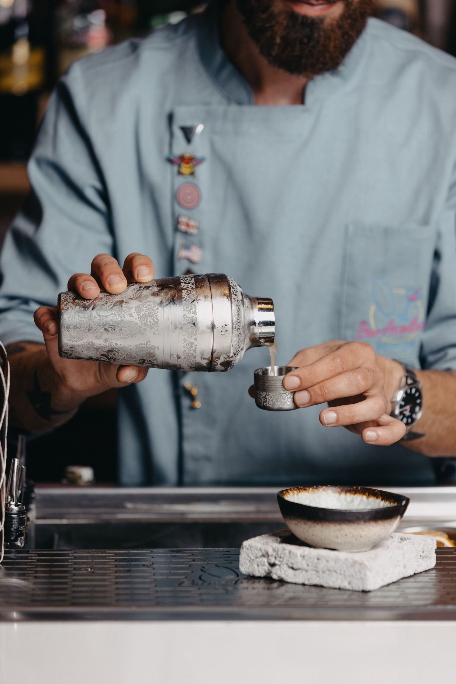 Close-up of bartender using cocktail shaker to prepare drinks.