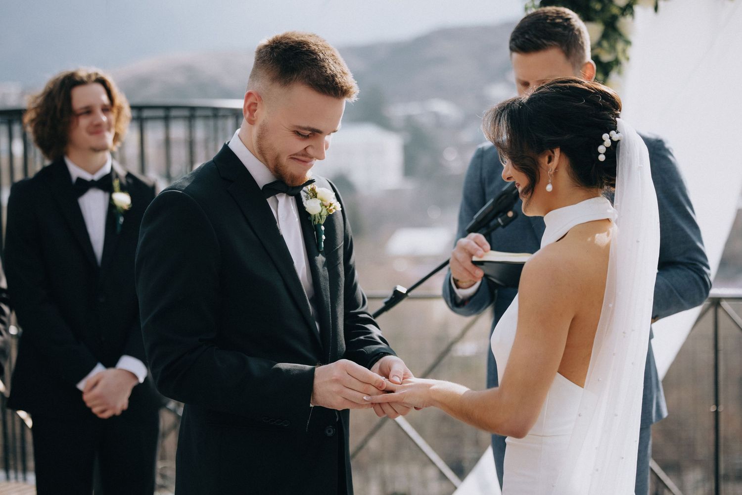 Wedding ceremony on outdoor terrace with couple exchanging rings during mountain vista ceremony.