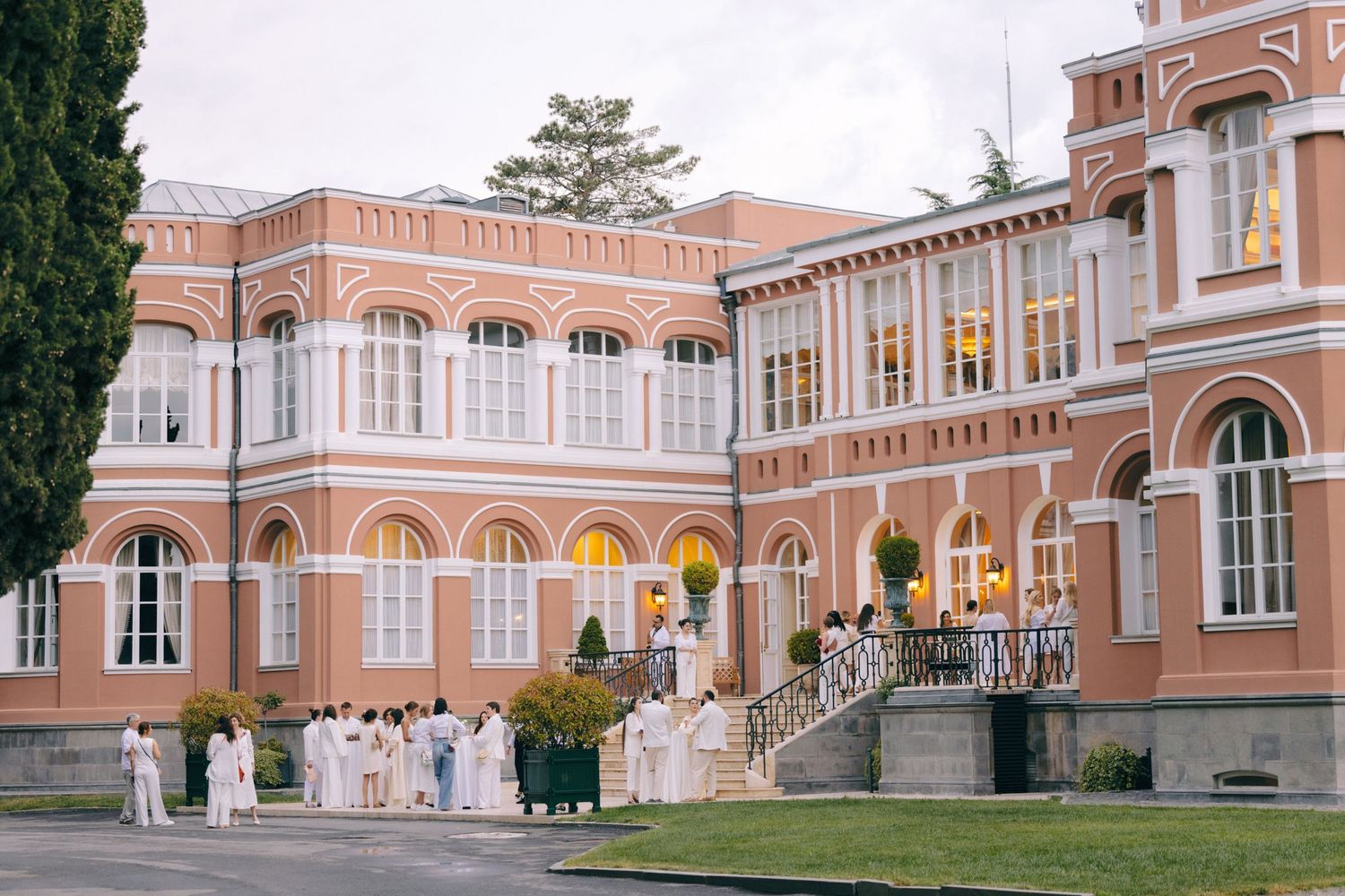 Panoramic view of a grand peach-colored historic building with arched windows and columns.