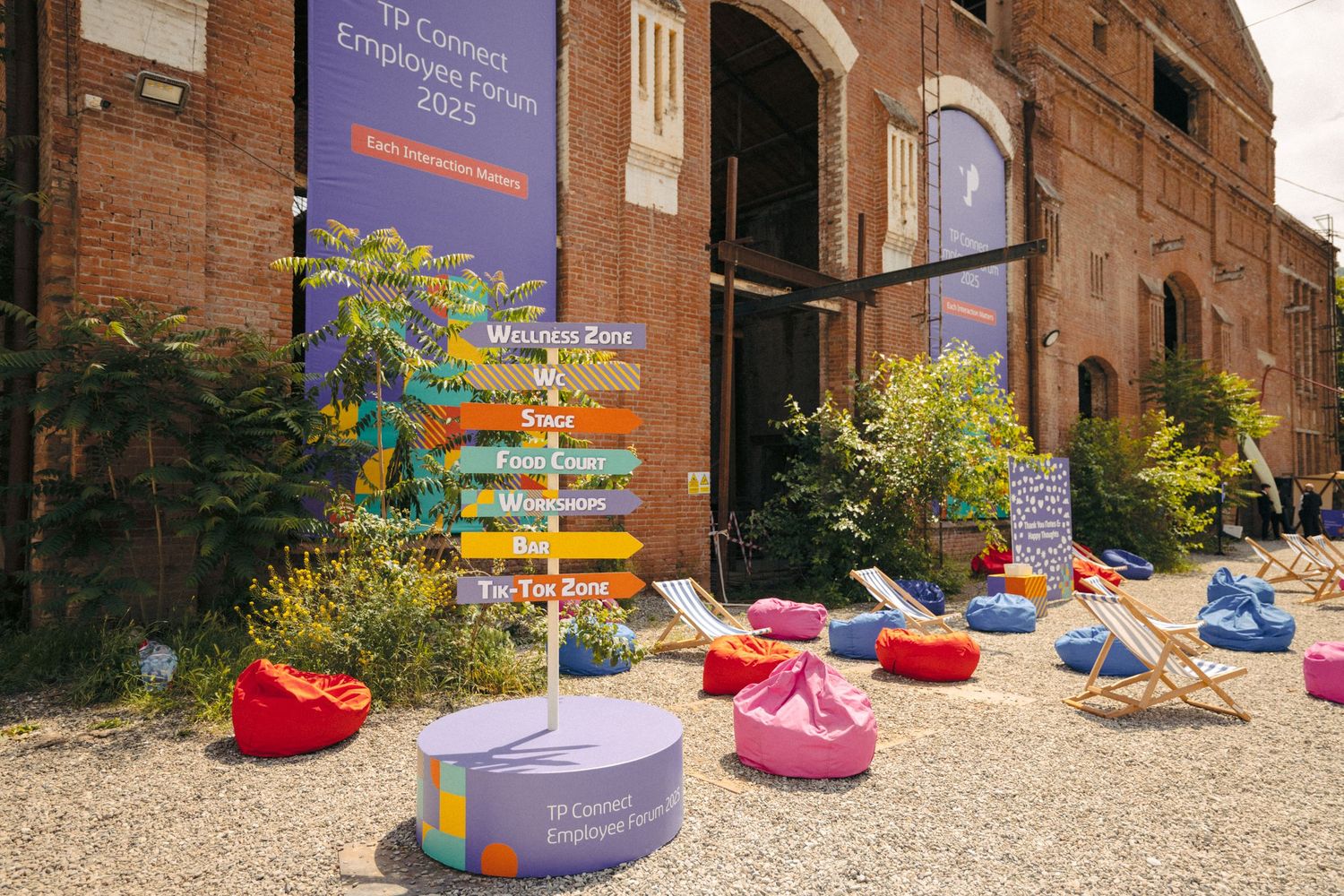 Outdoor venue setup with pink and blue bean bags arranged in front of a brick building.