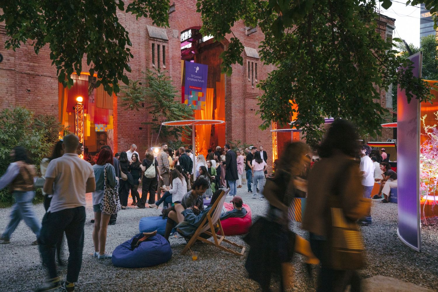 Evening outdoor gathering with brick walls and trees creating atmospheric lighting.