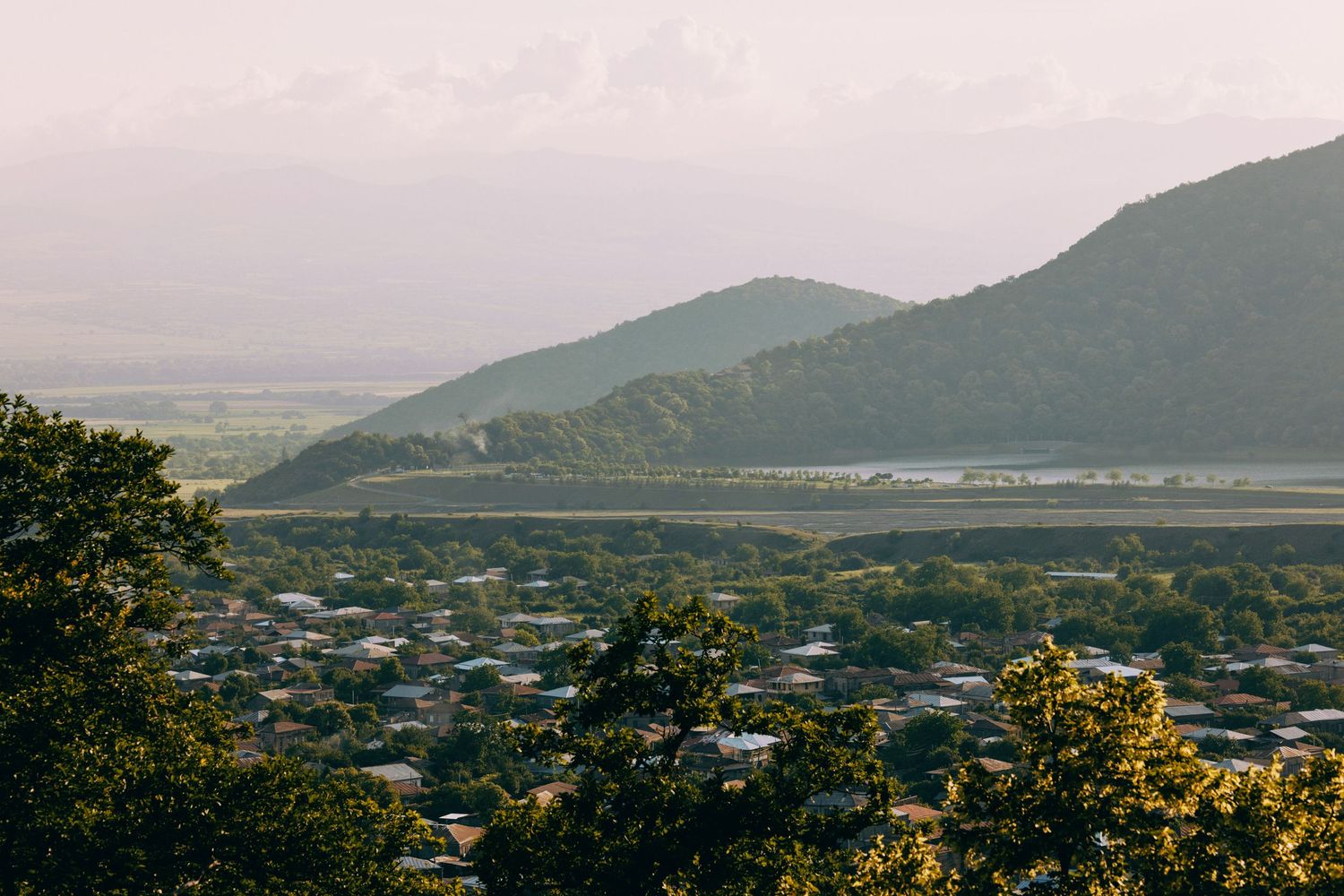 Scenic mountain landscape view overlooking a valley with distant buildings and natural terrain.