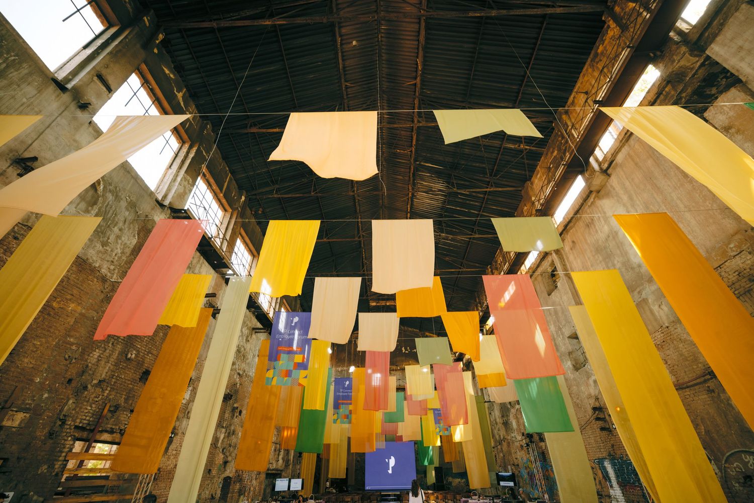 Colorful hanging banners in an industrial-style venue with high ceilings.