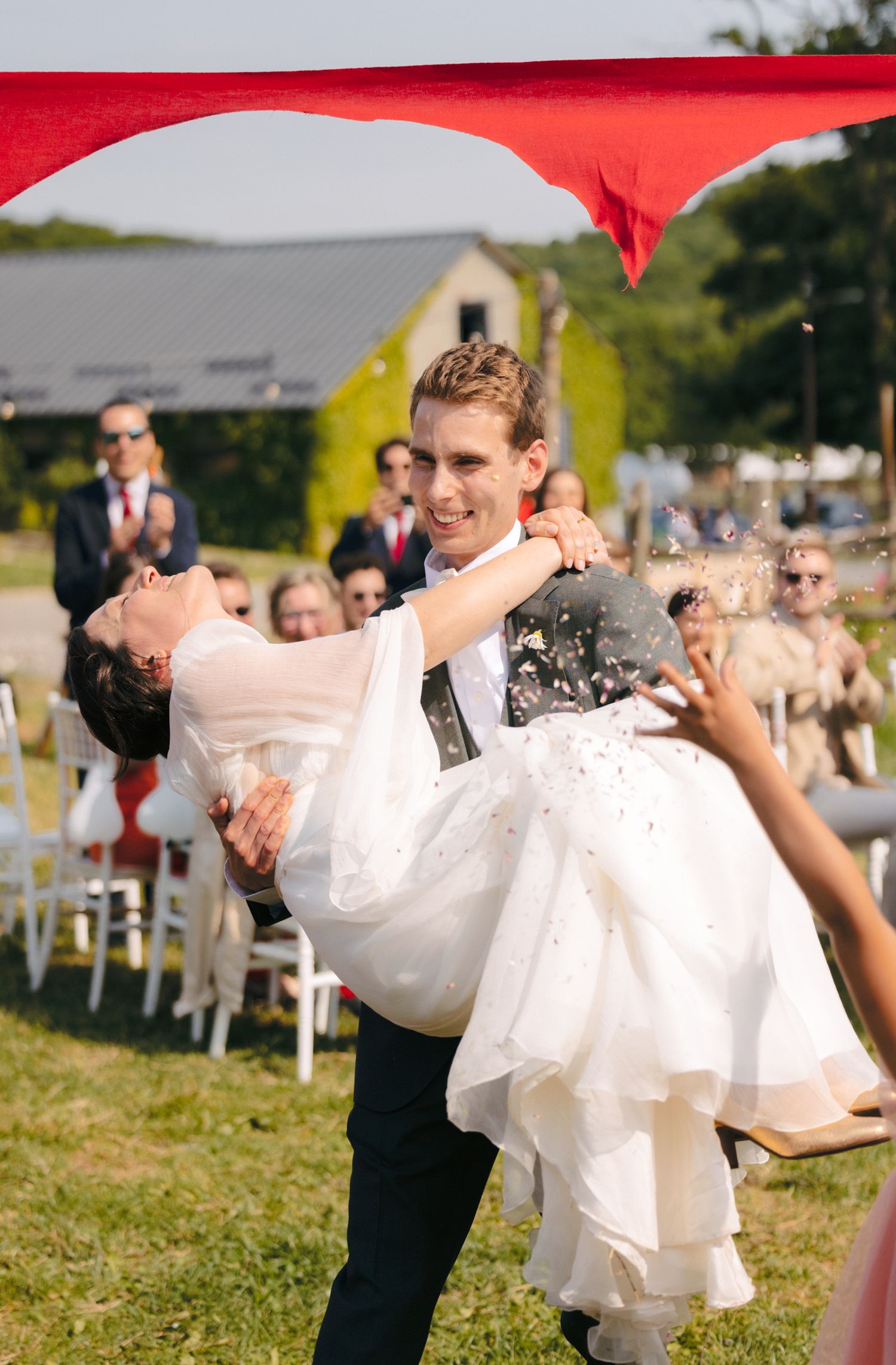 A couple performs a dramatic dip during their outdoor wedding dance on a grassy field.