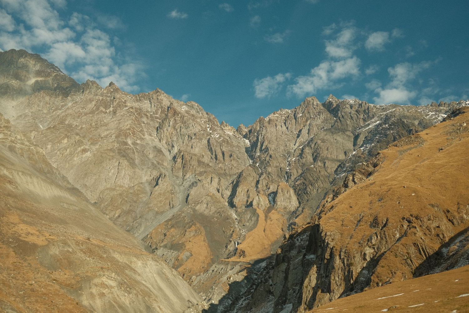 Rugged mountain peaks rise against blue sky in dramatic alpine landscape.