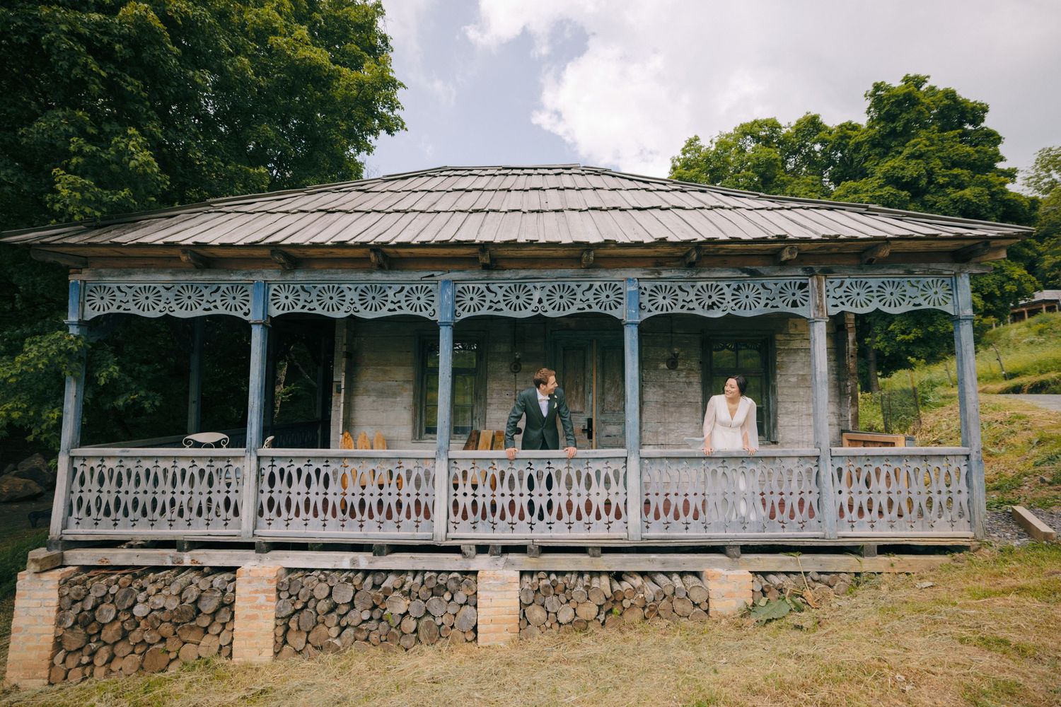 A charming vintage gazebo with ornate white trim and wooden shingles in a garden setting.