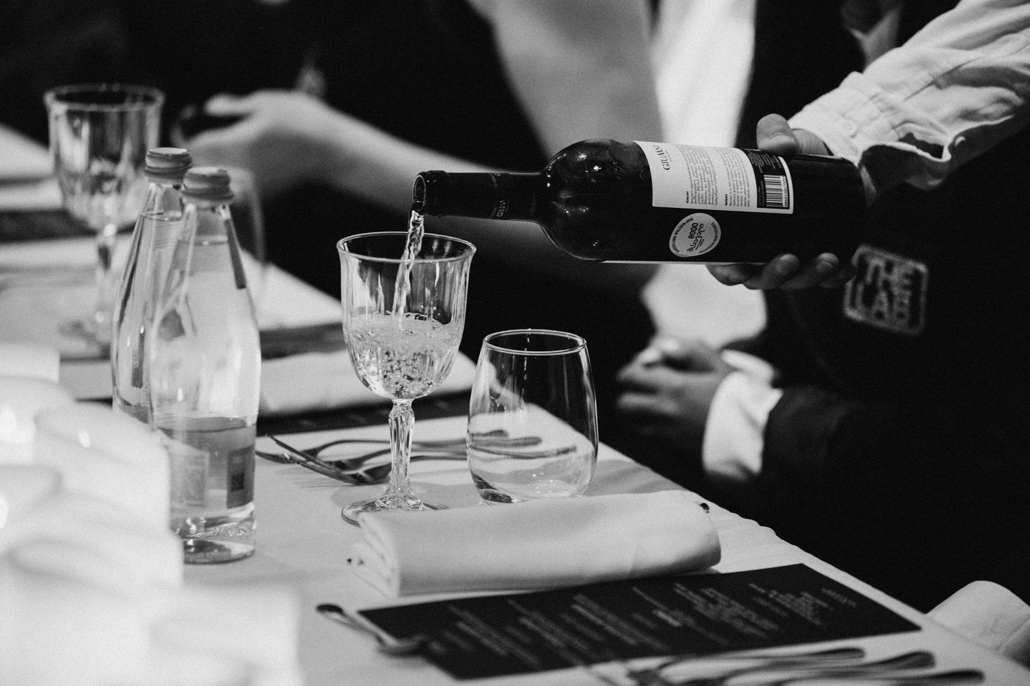 Black and white image of table settings and glassware at an event.