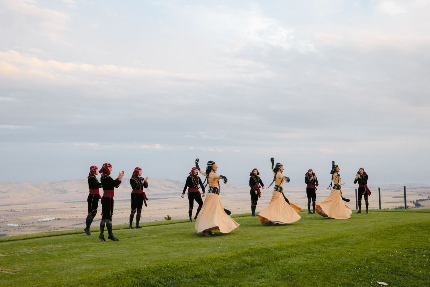 People standing in silhouette on a hilltop against an evening sky.