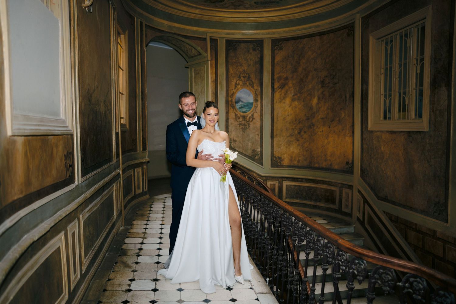 Couple on vintage tiled floor in elegant historic building with ornate walls.