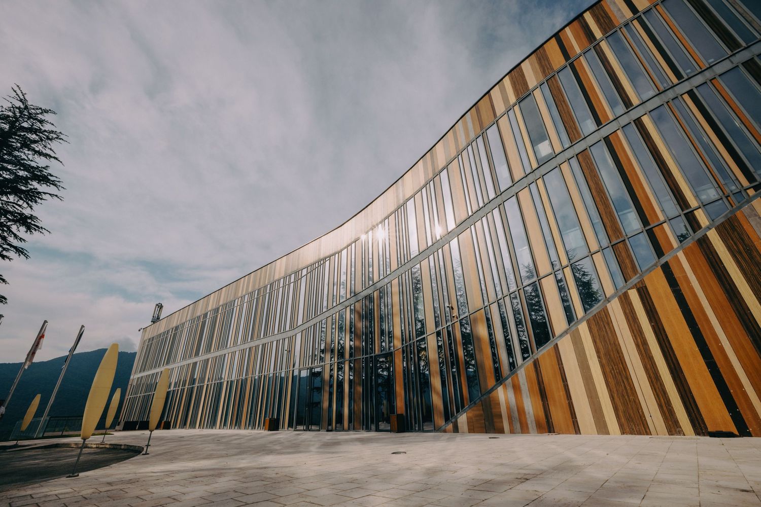 Contemporary building facade with geometric wood and glass elements against blue sky.
