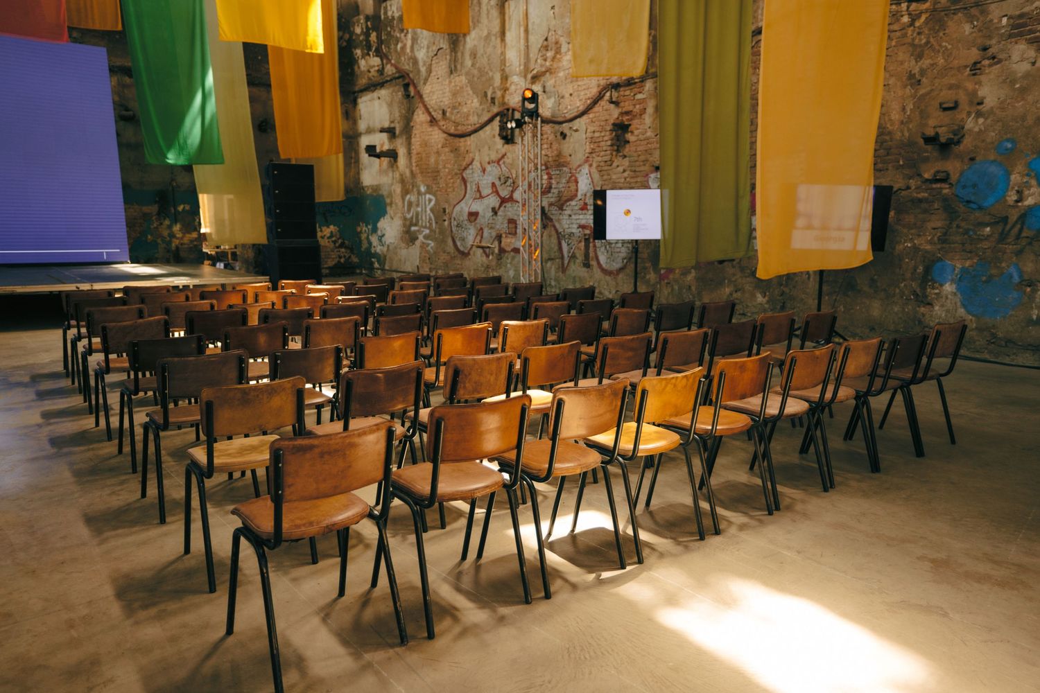 Conference room setup with rows of chairs against colorful wall decorations.