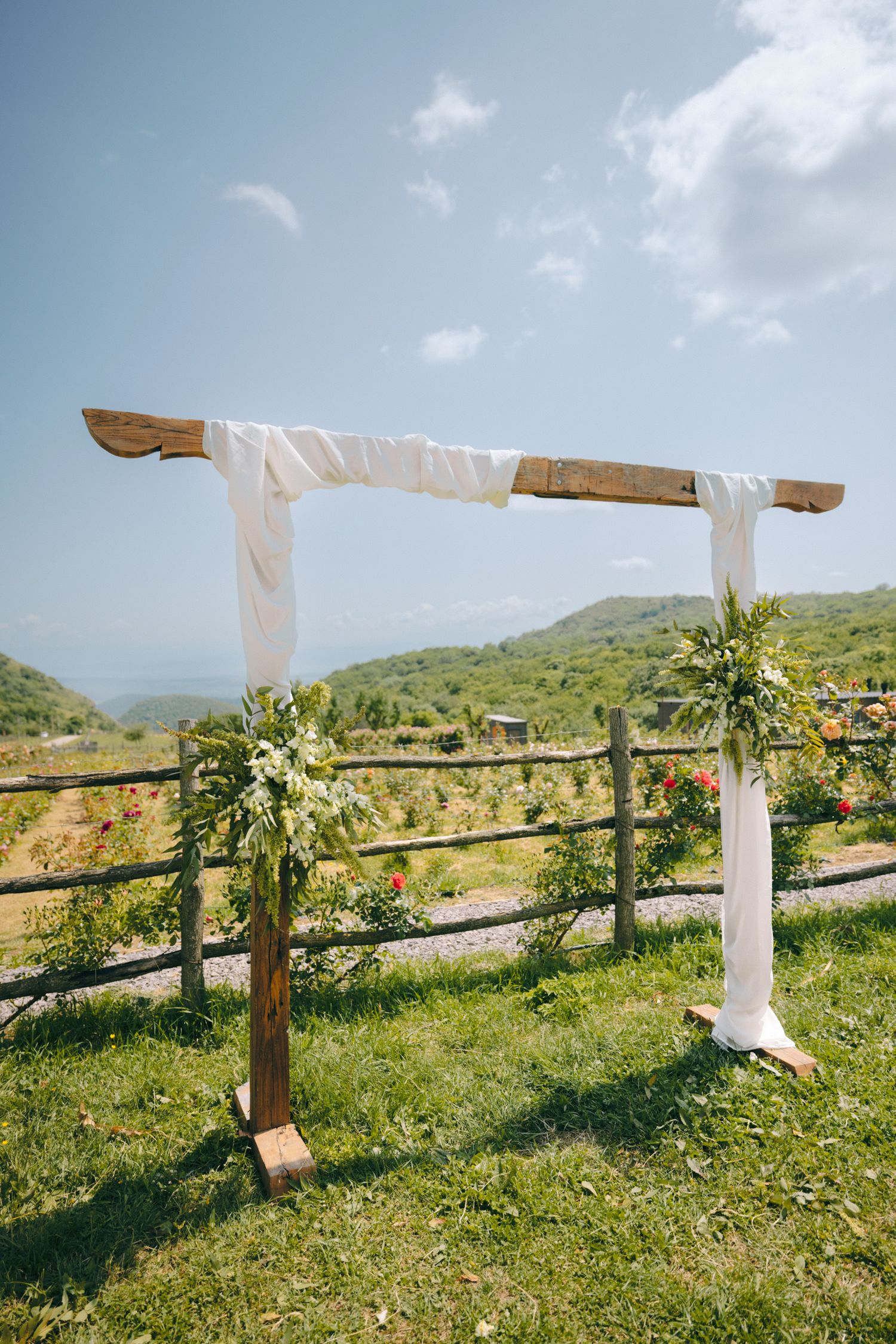 A simple wooden wedding arch draped with white fabric overlooking mountain views.