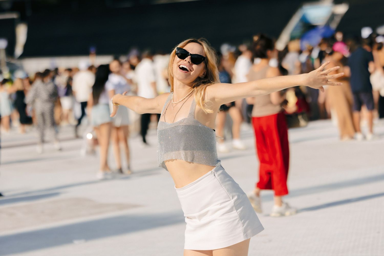 Festival attendee dances joyfully in a summer outfit at an outdoor music event.