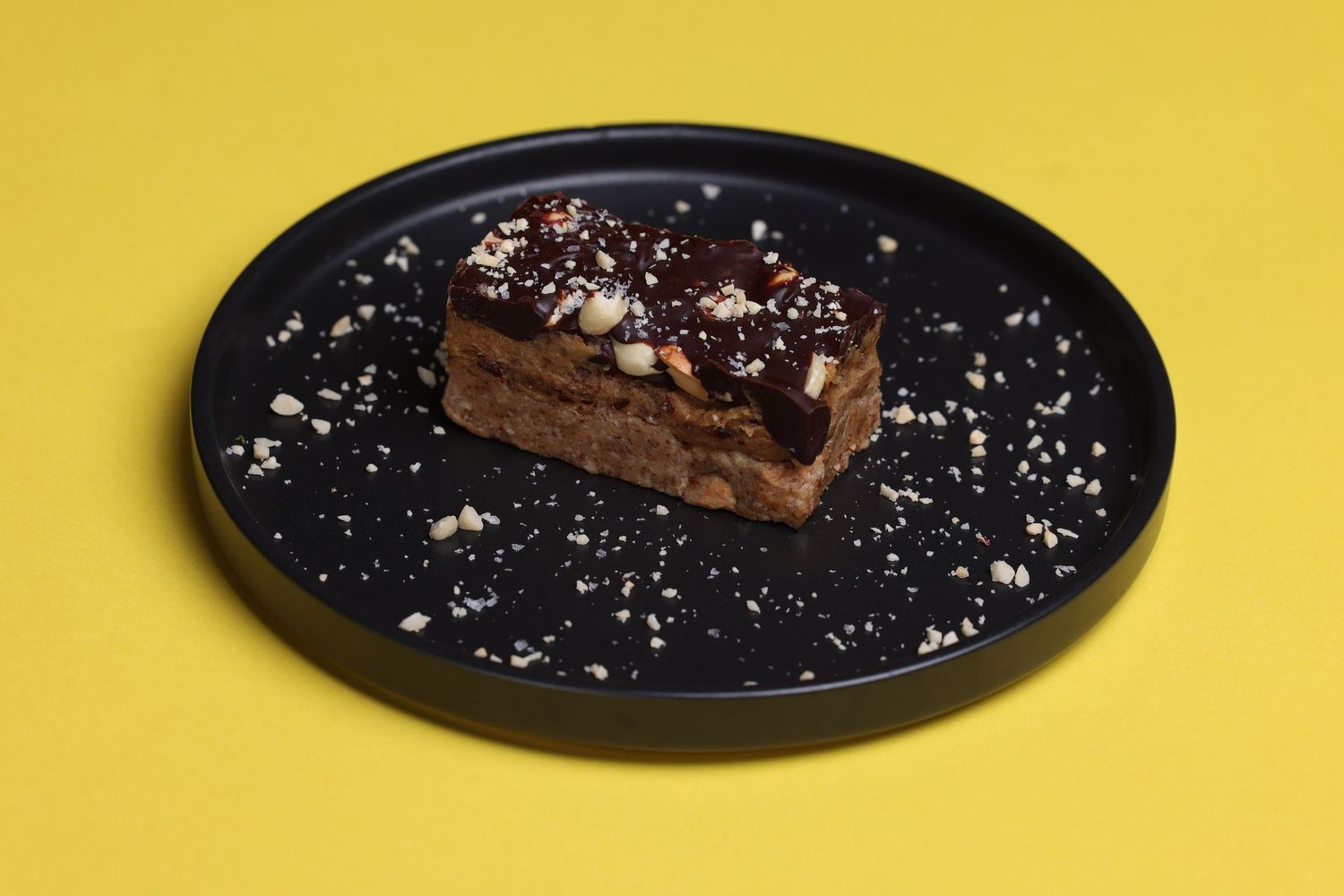 Sequence of dessert plating showing a cake slice with garnish on black plate against yellow background.