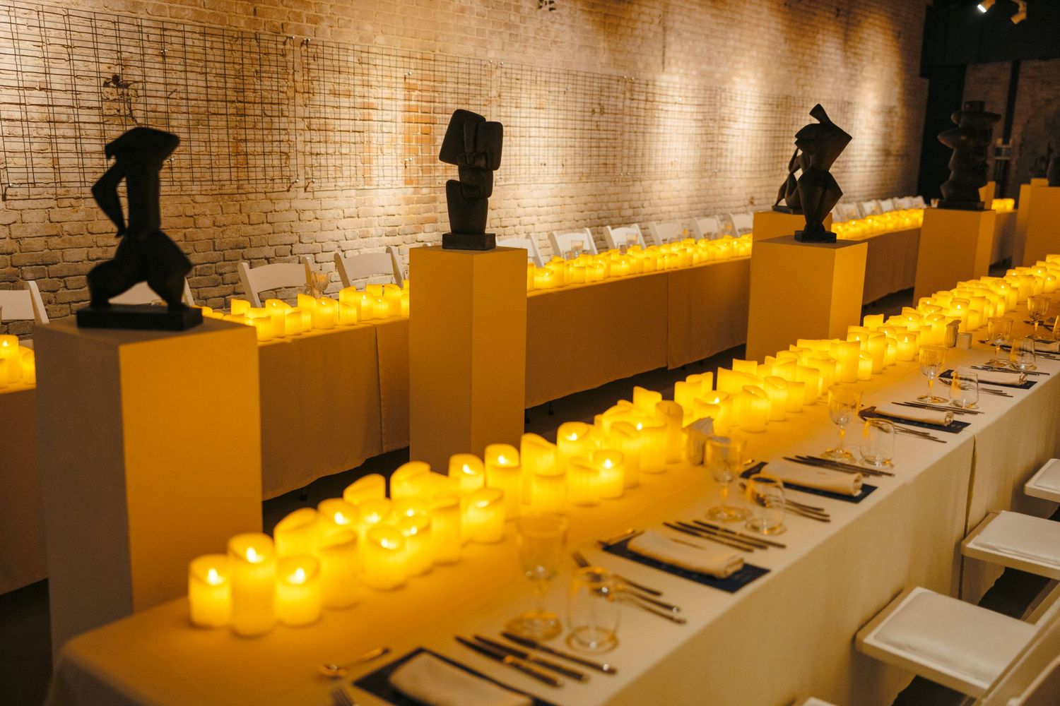 Restaurant interior with yellow accent lighting and formal place settings.