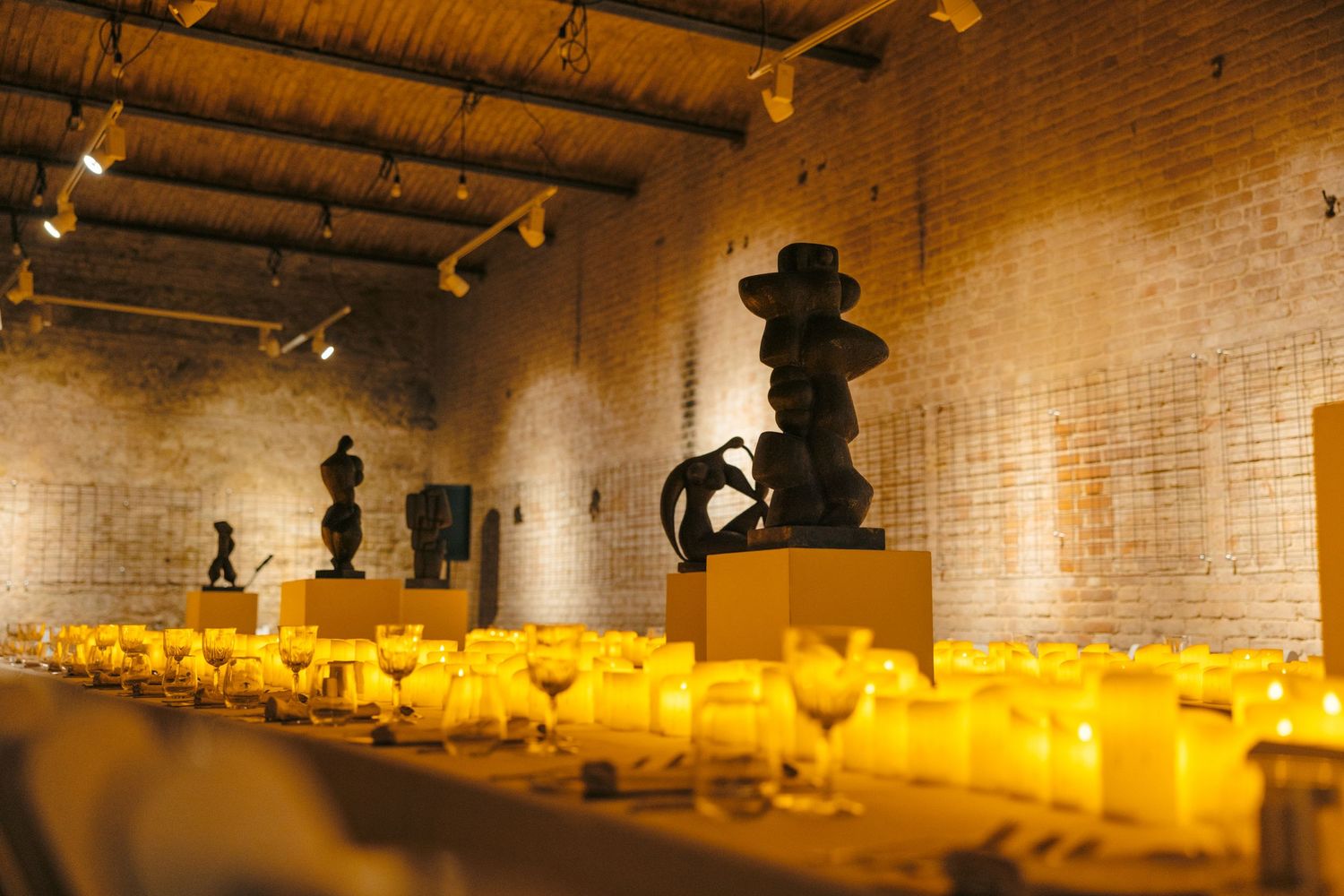 Rustic brick-walled dining room with dramatic lighting and table settings.