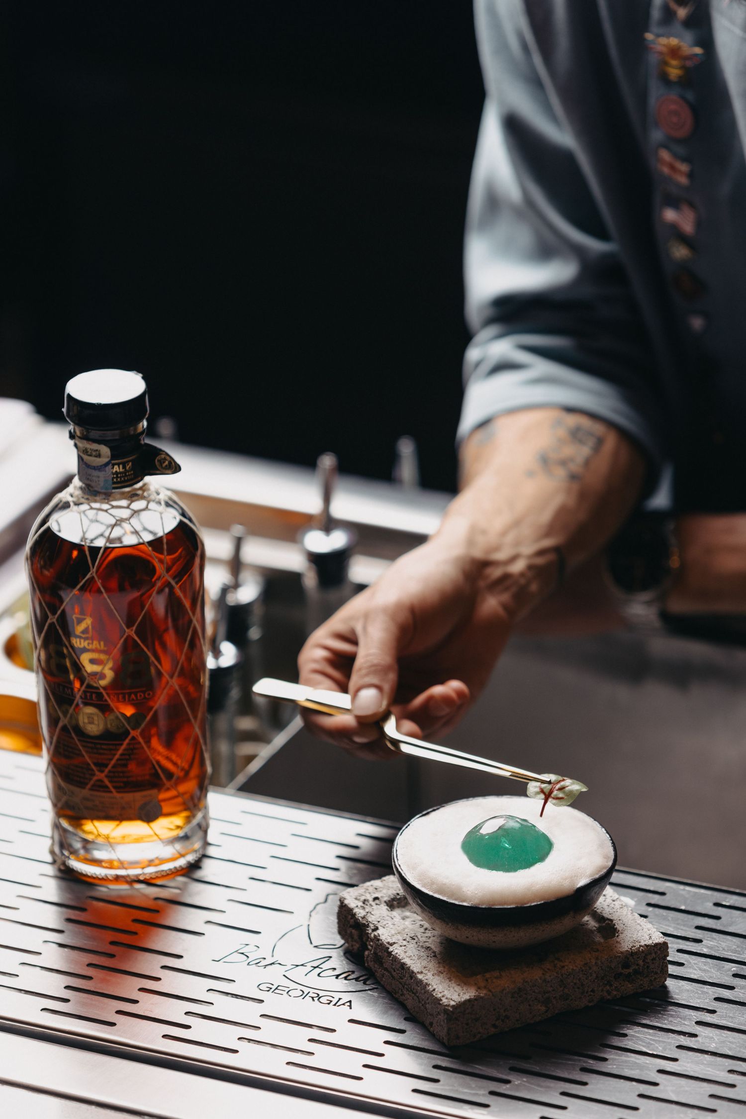 Close-up of hands preparing cocktails with decorative glass bottles on a bar counter.
