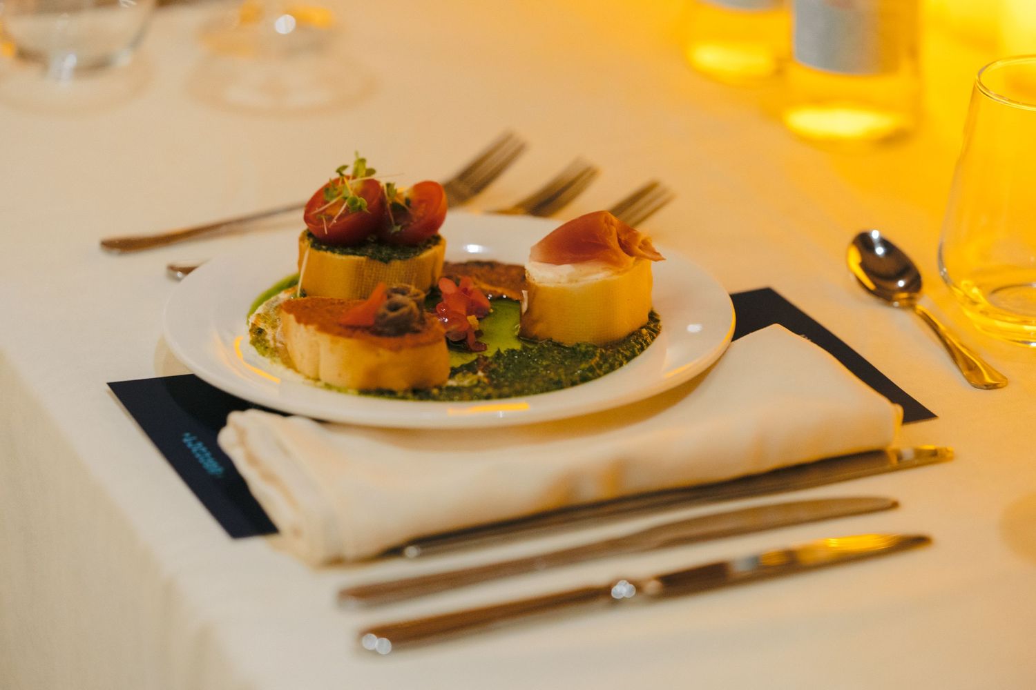 Plated gourmet dish served on white china with warm ambient lighting.