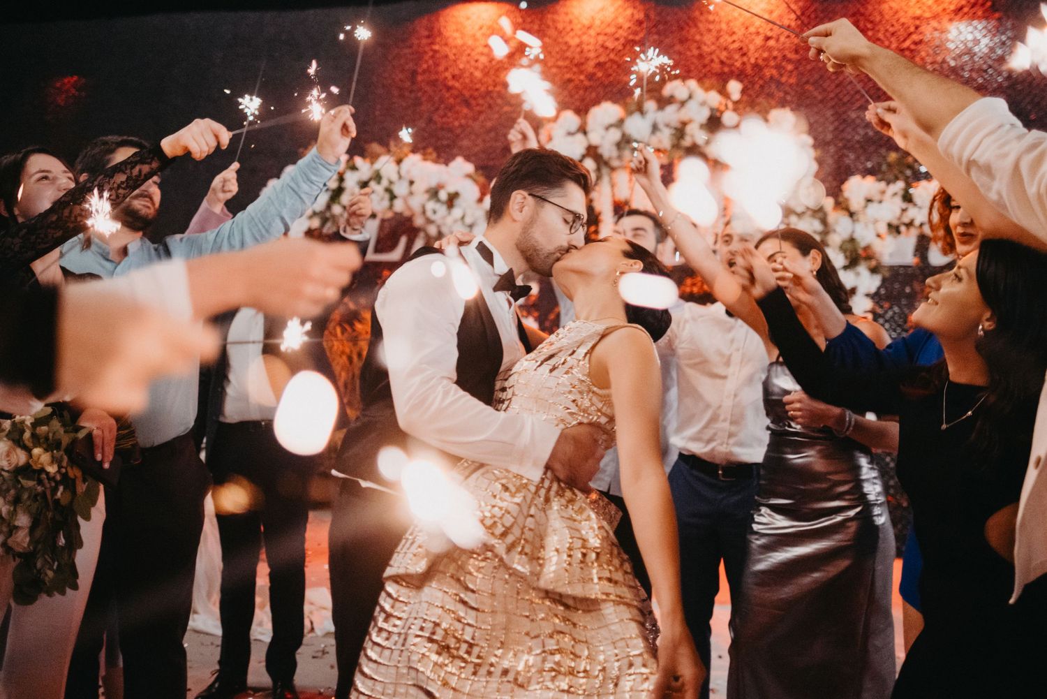 Couple sharing their first dance at a wedding reception surrounded by guests with sparklers.