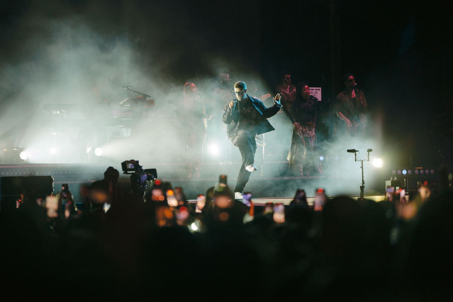 Silhouetted concert performance with atmospheric fog and dramatic backlighting creating a moody ambiance.